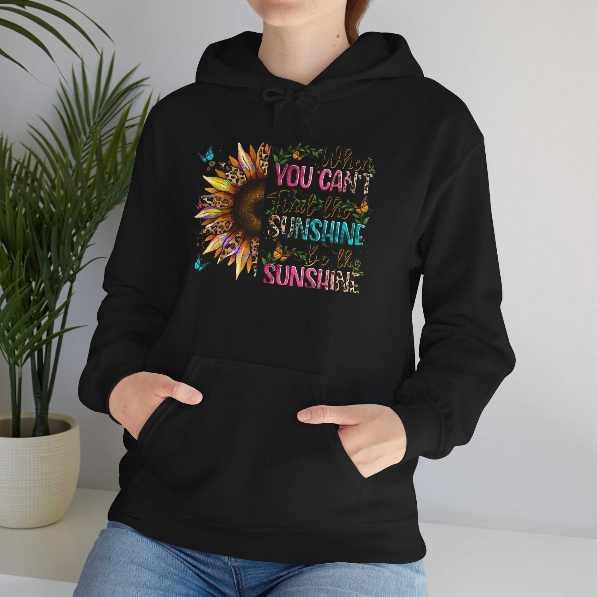 Black sunflower quote hoodie with colorful inspirational text and kangaroo pocket worn by person