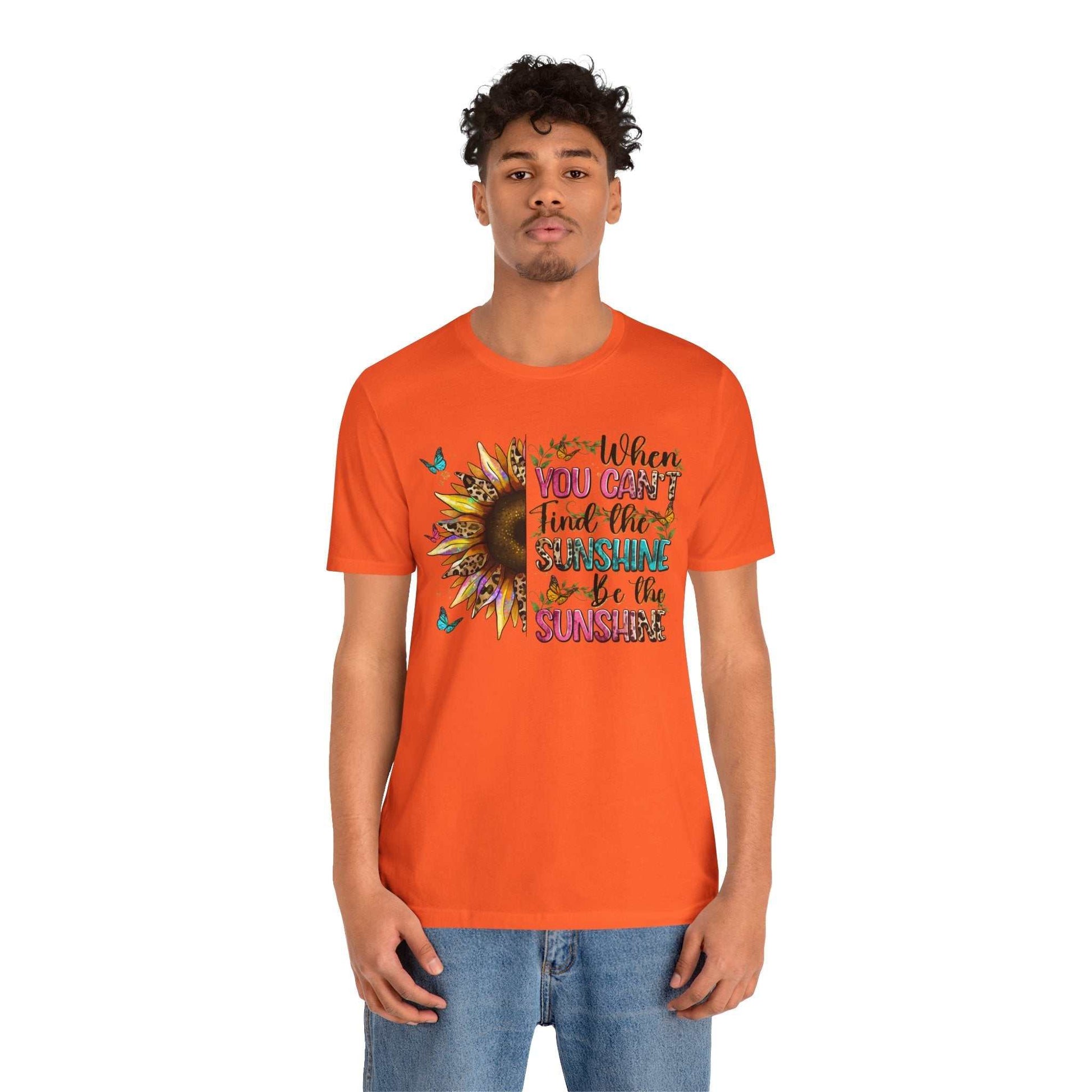 Young man wearing orange Sunshine Quote Tee with vibrant sunflower and motivational text design