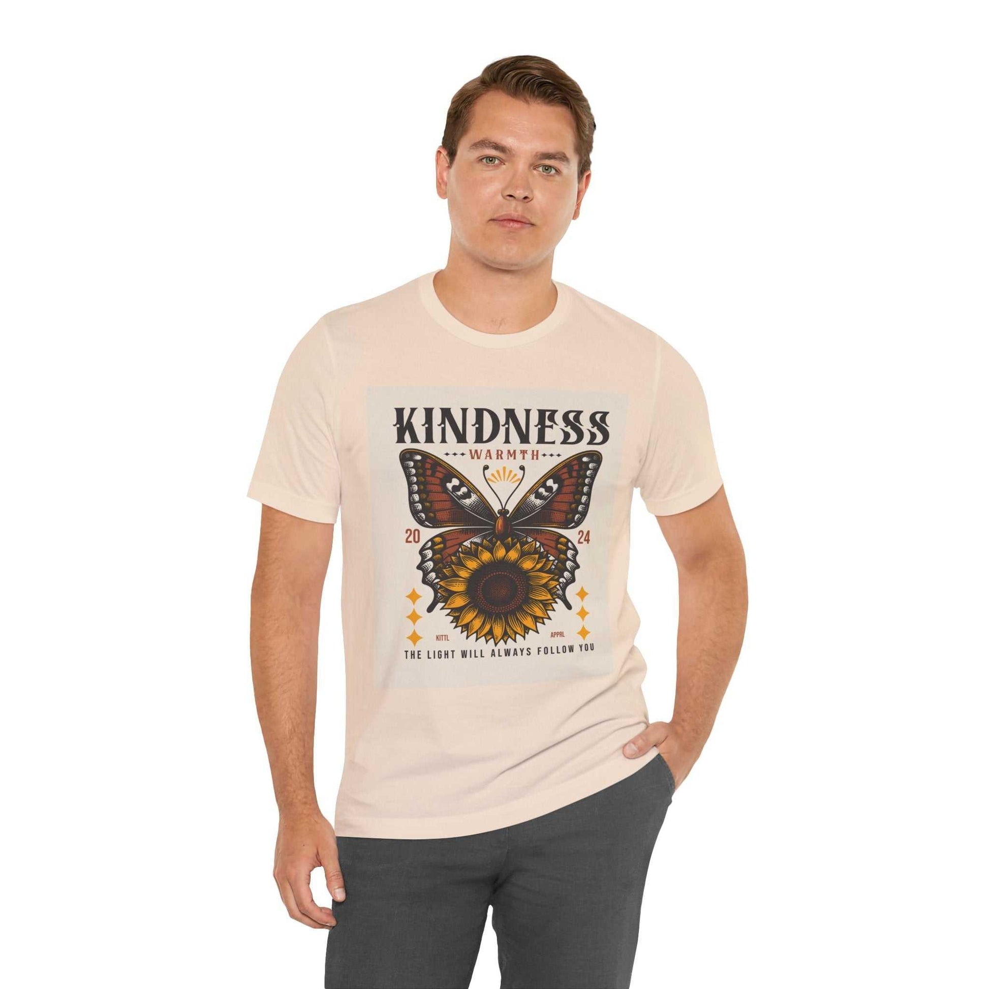 Man wearing a Kindness Butterfly Tee featuring a butterfly and sunflower design with the text "Kindness warmth" and "The light will always follow you" on a light-colored short sleeve shirt