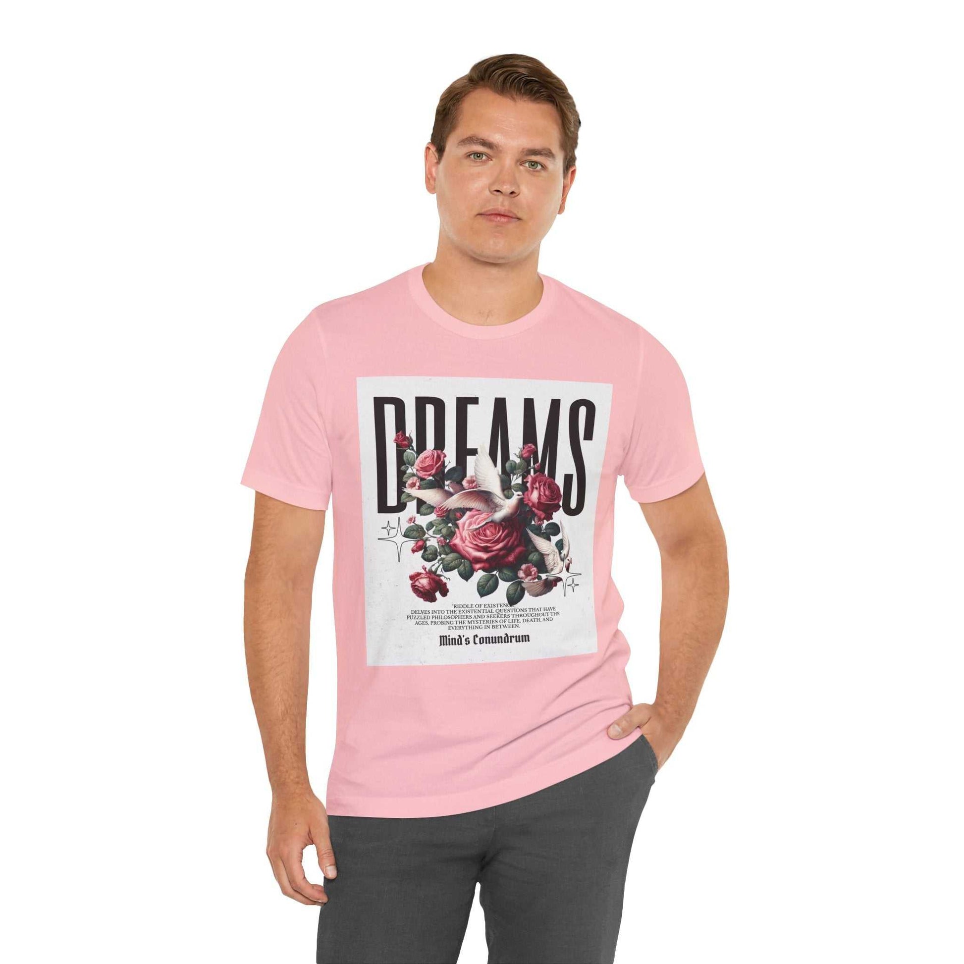 Man wearing a pink Dreams Floral Tee with rose floral design and bold typography on front, paired with dark pants.