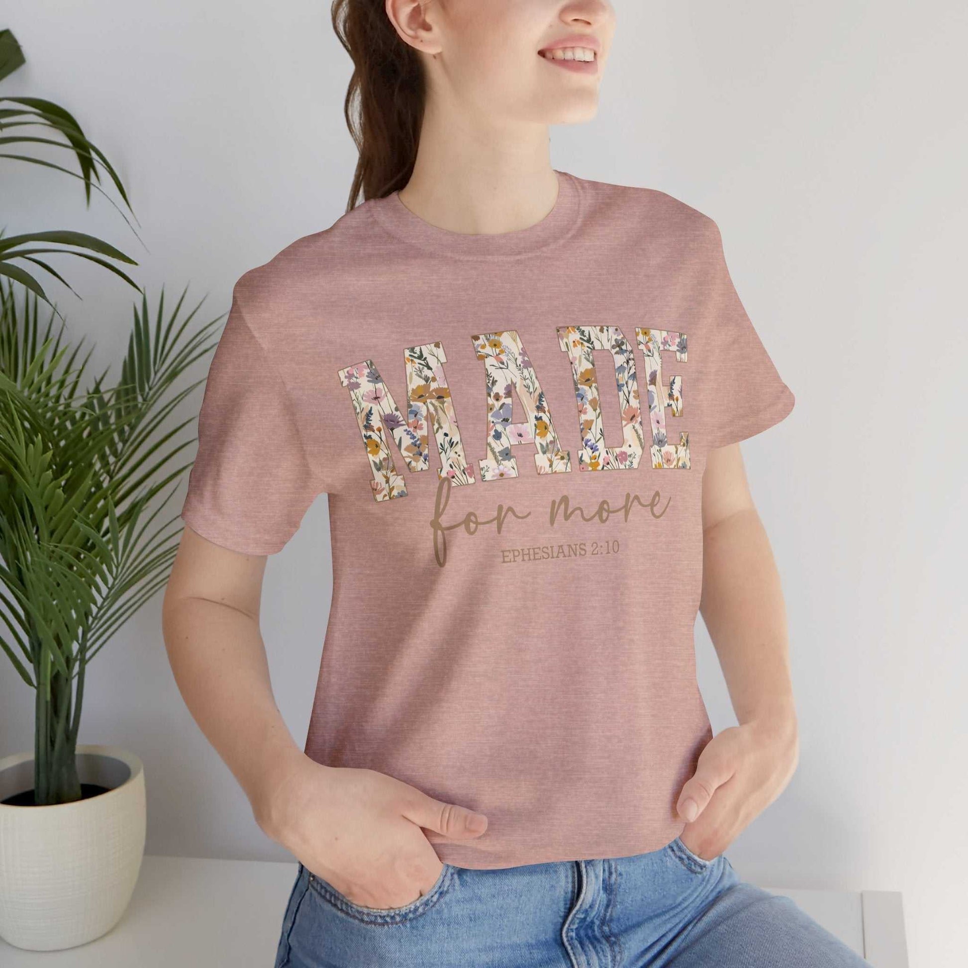 Woman wearing pink Made for More Tee with floral letters and Ephesians 2:10 text, casual style