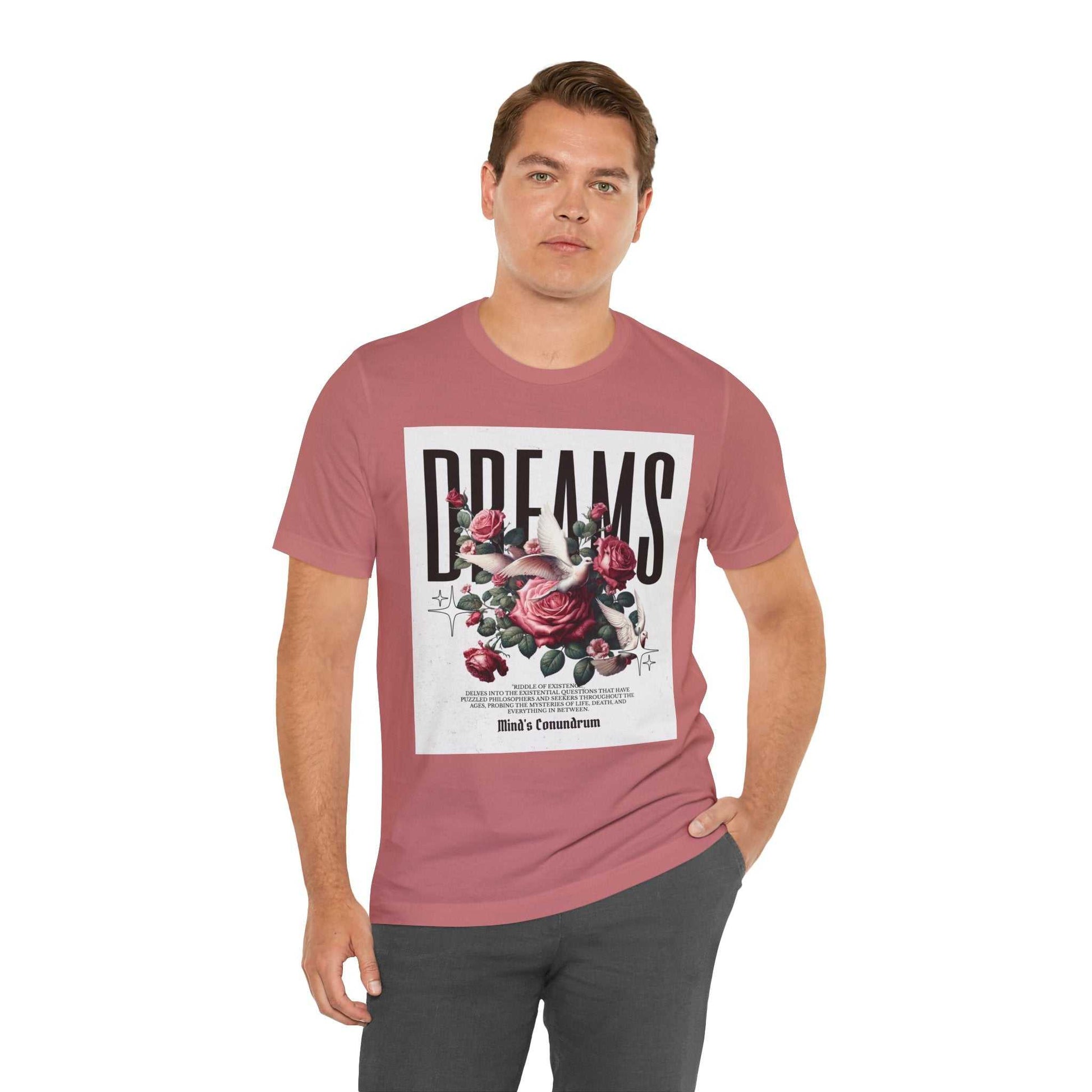 Man wearing a dusty rose Dreams Floral Tee with bold typography and floral design on front, paired with dark pants.
