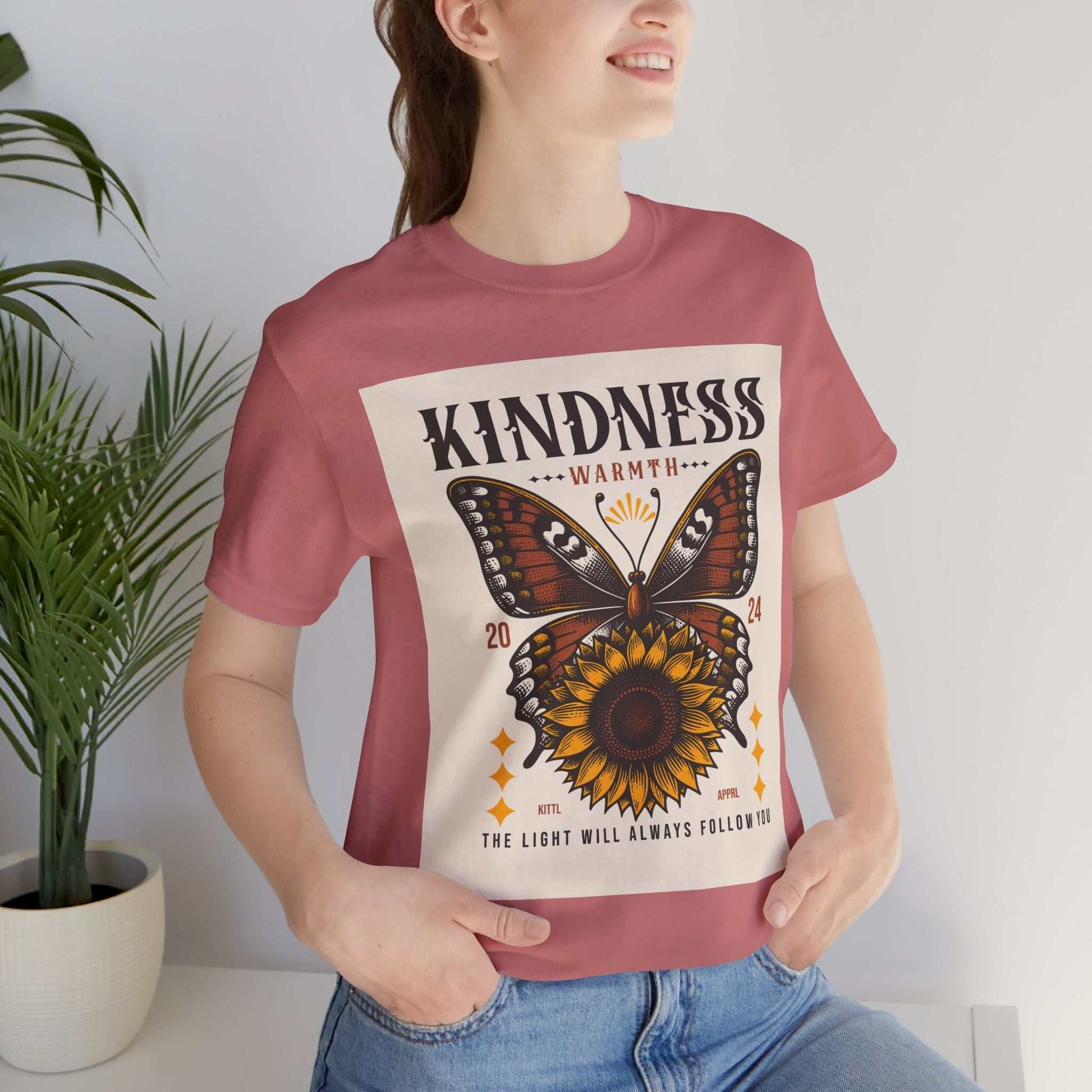 Woman wearing pink Kindness Butterfly Tee with butterfly and sunflower graphic and positive message