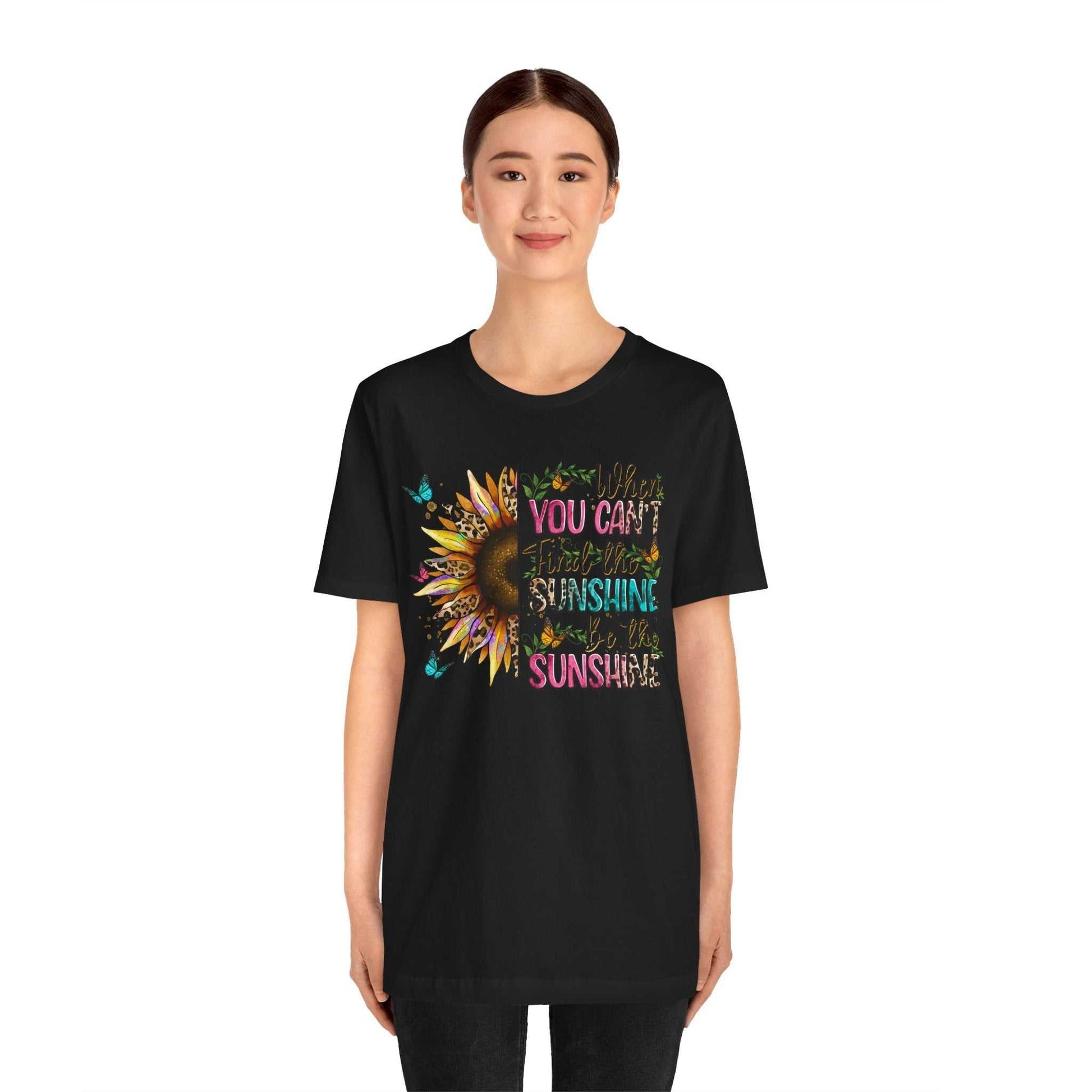 Woman wearing black Sunshine Quote Tee with colorful sunflower and uplifting text design