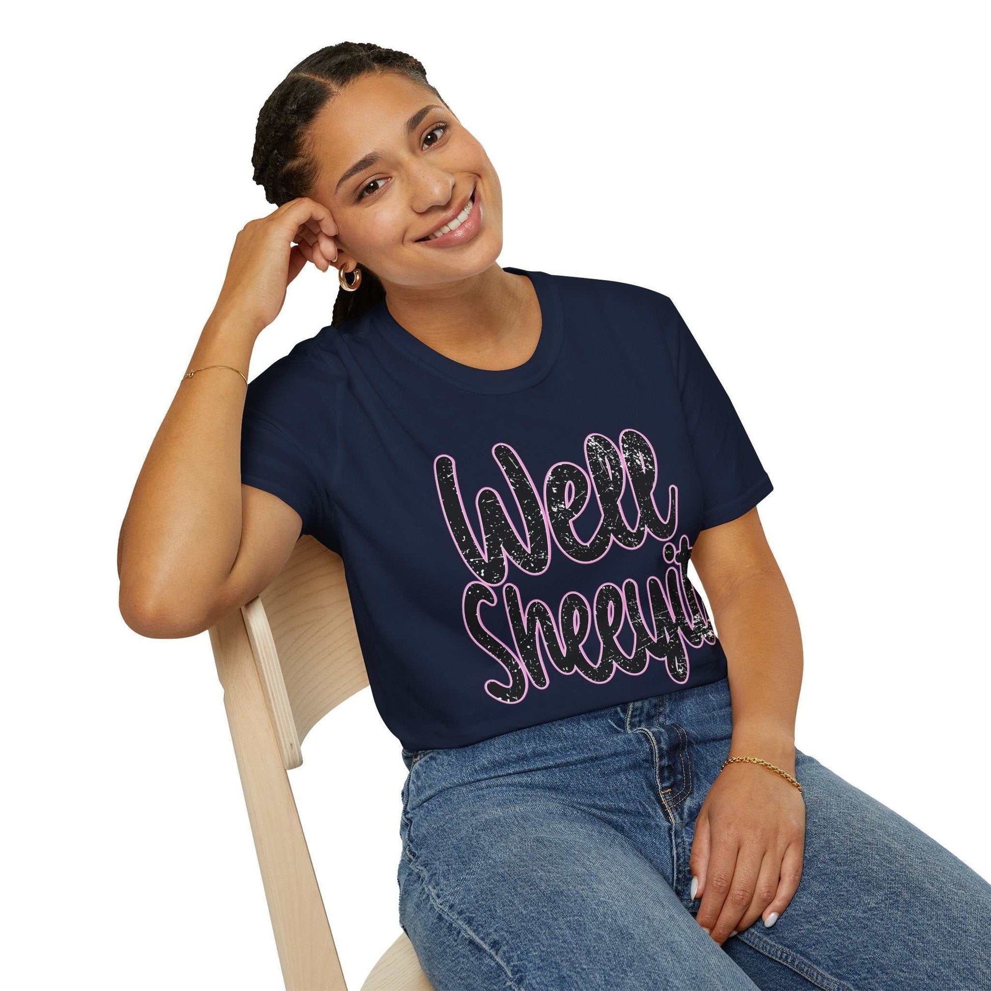 Woman wearing navy casual statement tee with funny "Well Sheeyit" print sitting on chair smiling