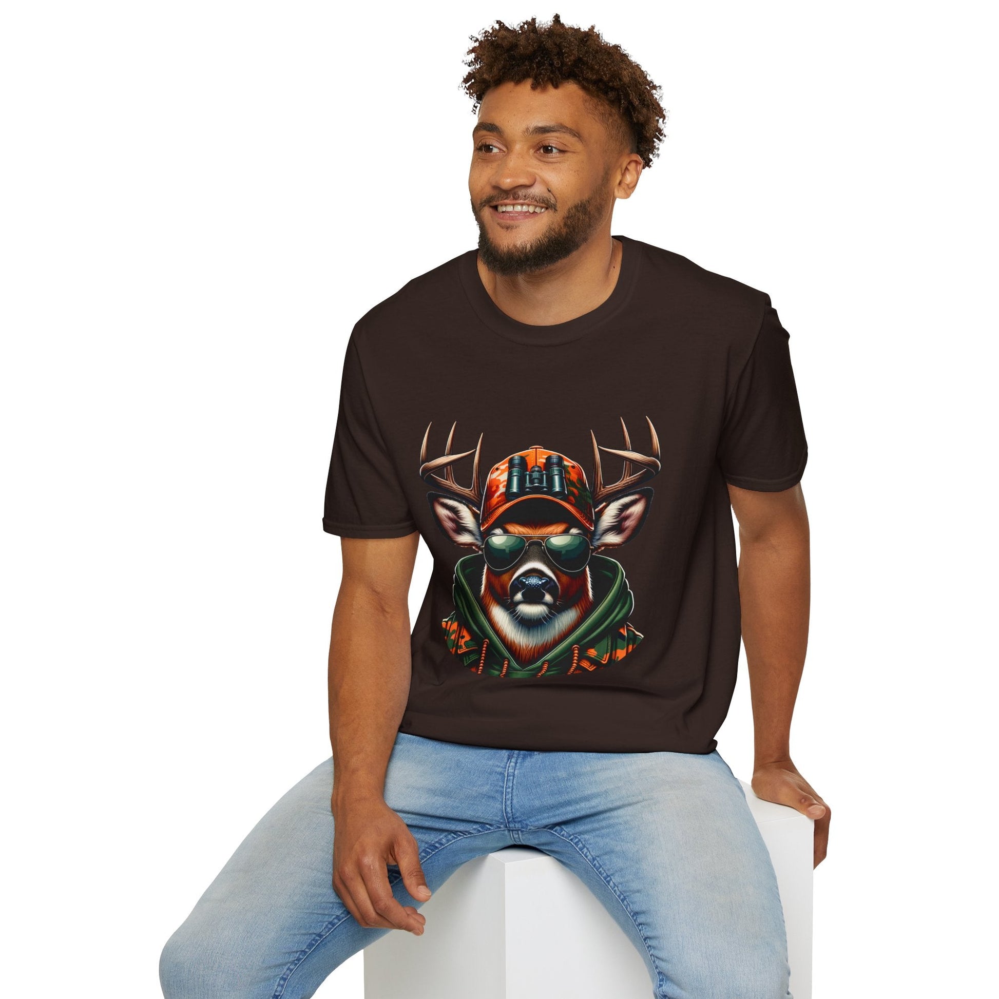Man wearing black Hunting Enthusiast T-Shirt with deer graphic in sunglasses and camo hat sitting on white block
