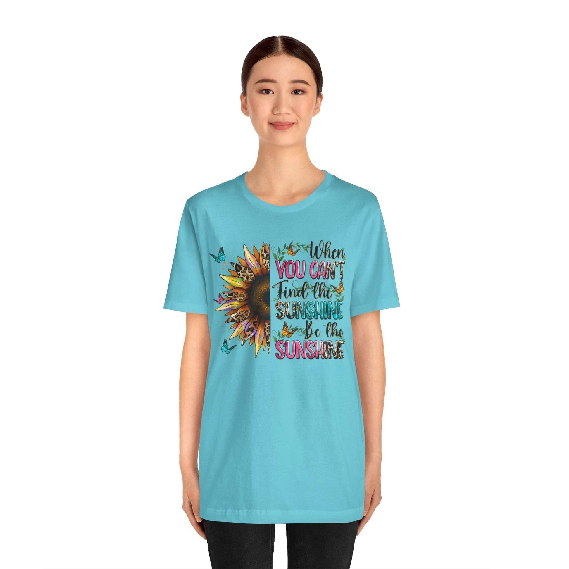 Woman wearing light blue Sunshine Quote Tee with sunflower and motivational text design