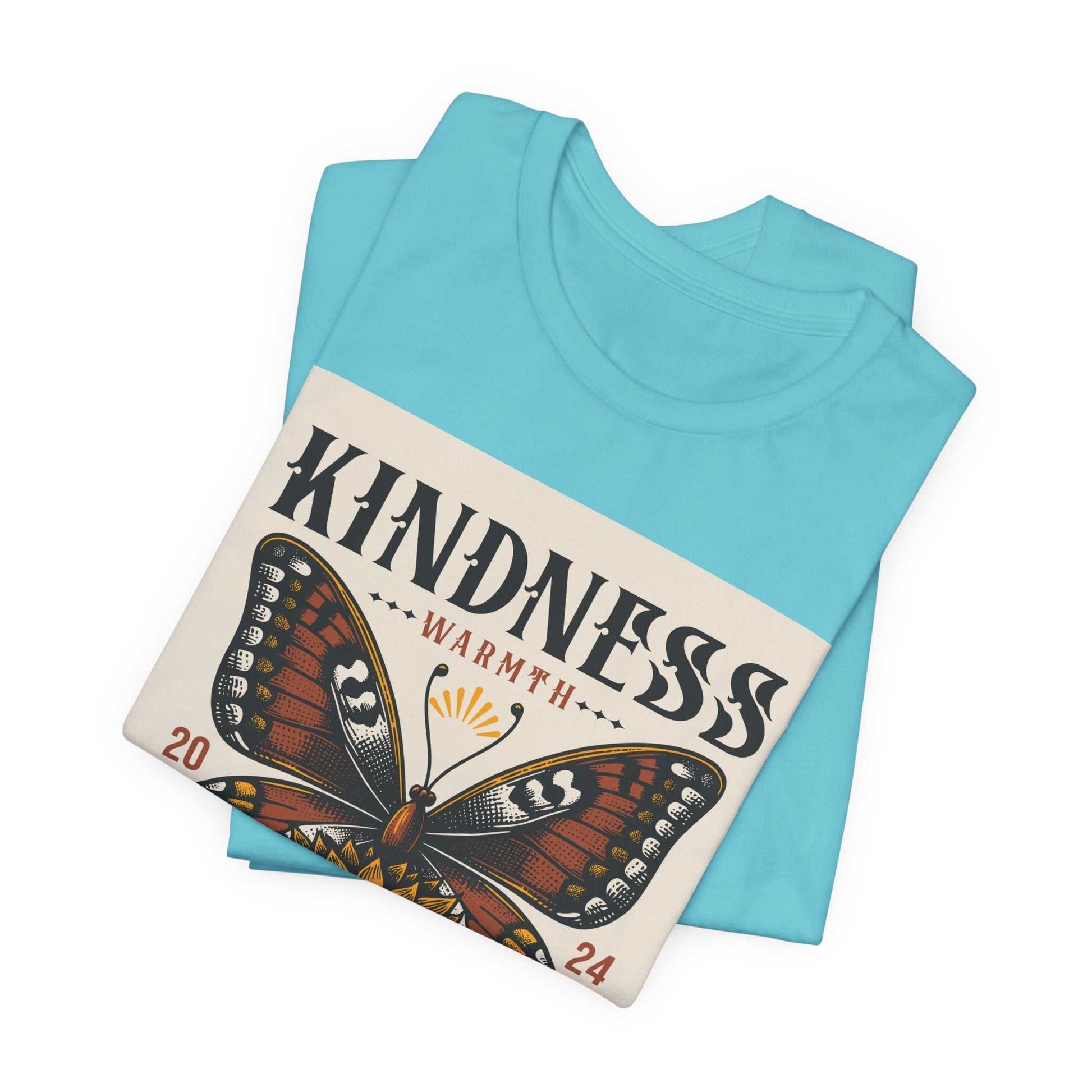 Folded light blue Kindness Butterfly Tee featuring a large butterfly graphic and "Kindness Warmth 2024" text on the front