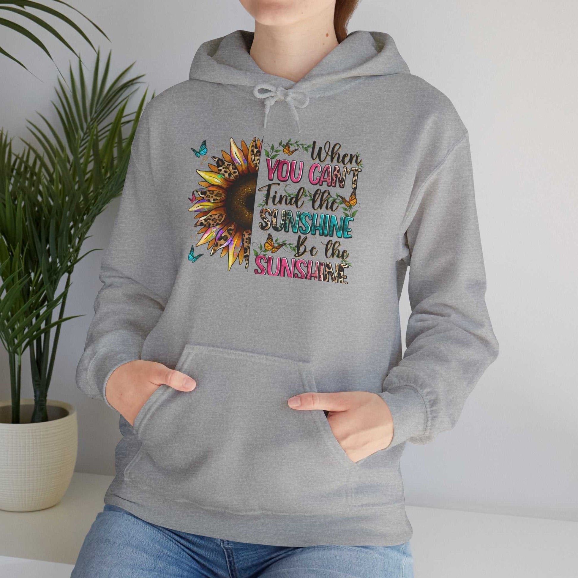 Gray sunflower quote hoodie with inspirational colorful text and butterfly design, worn by person with hands in front pocket