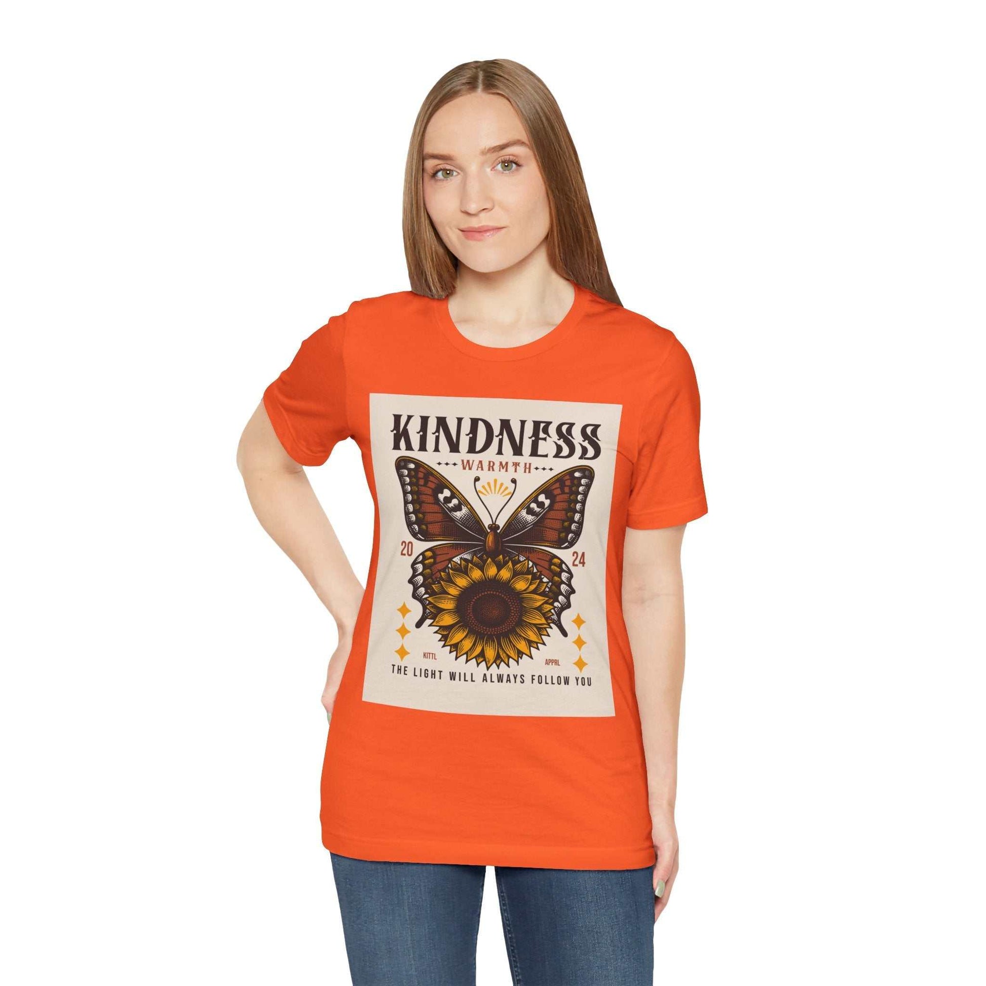 Woman wearing orange Kindness Butterfly Tee with butterfly and sunflower graphic design on the front