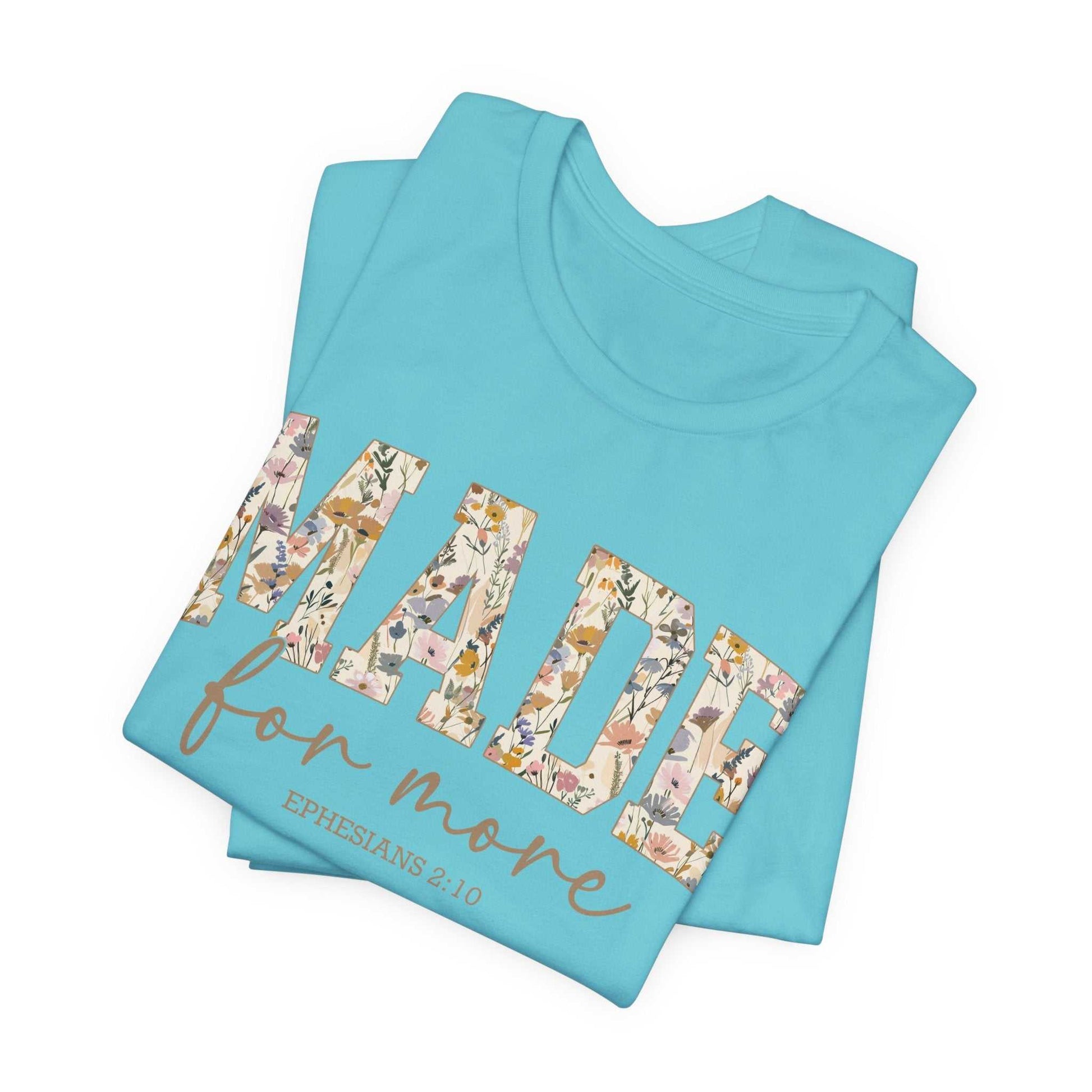 Folded light blue Made for More Tee with floral patterned text and scripture reference on front