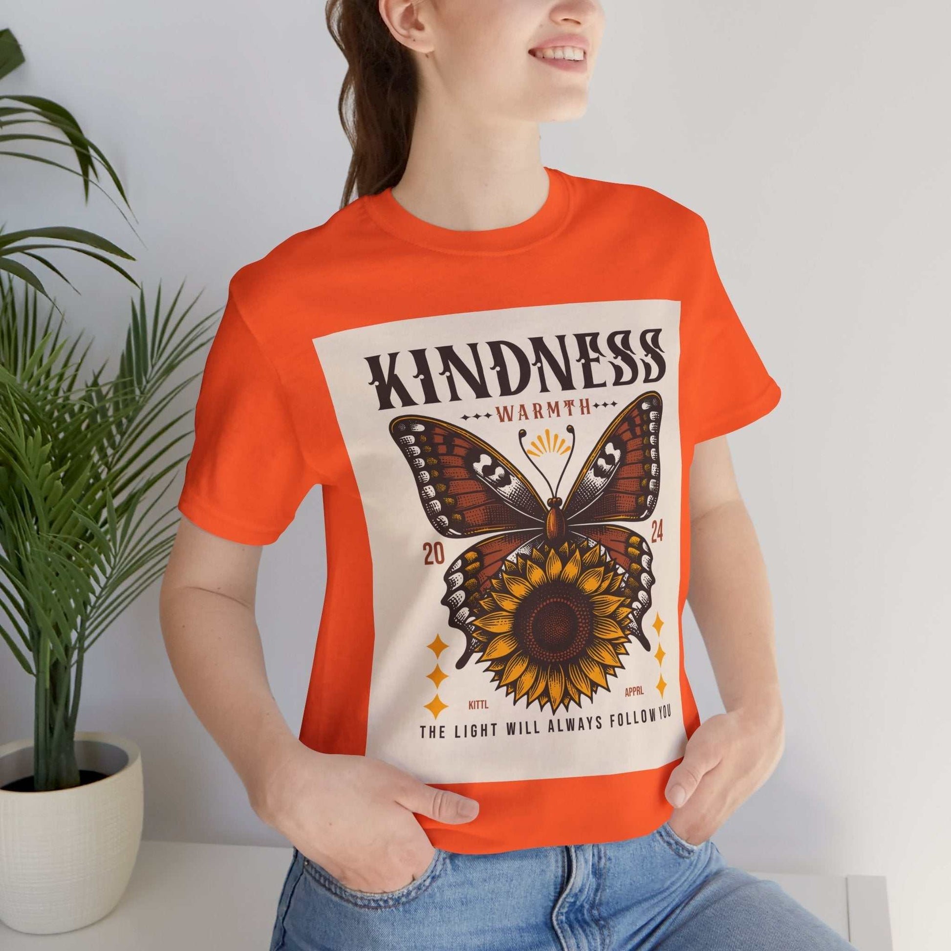 Woman wearing orange Kindness Butterfly Tee with butterfly and sunflower design and positivity message
