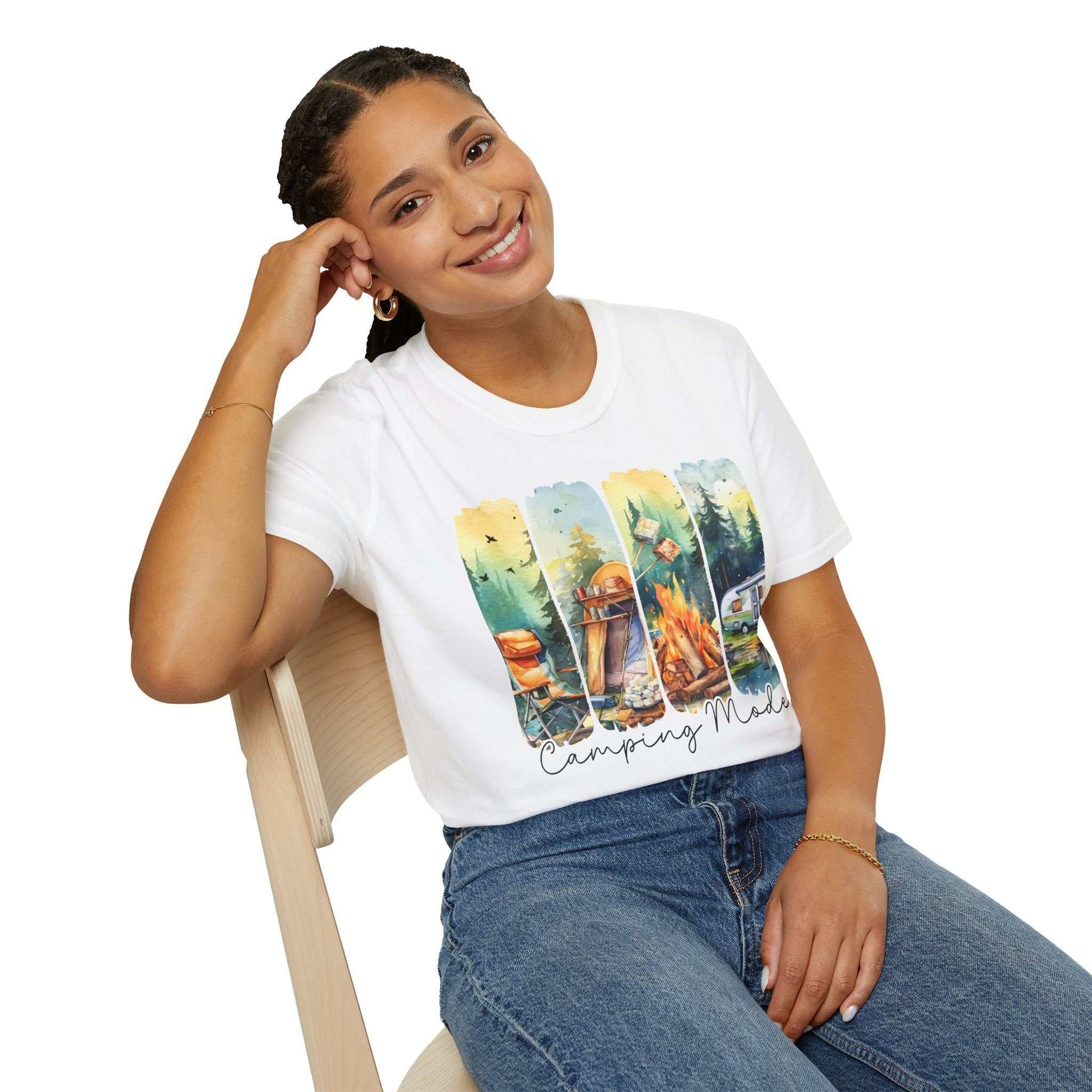 Woman wearing white Camping Adventure Unisex T-Shirt with colorful camping-themed design sitting on chair smiling