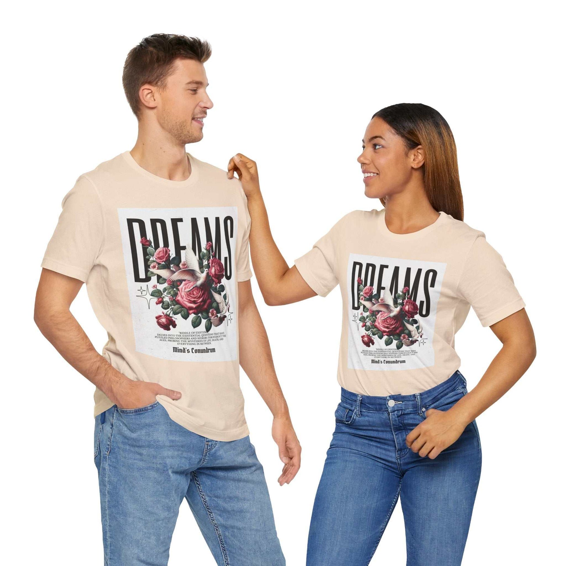 Unisex beige Dreams Floral Tee with bold typography and floral design, worn by male and female models in casual jeans.