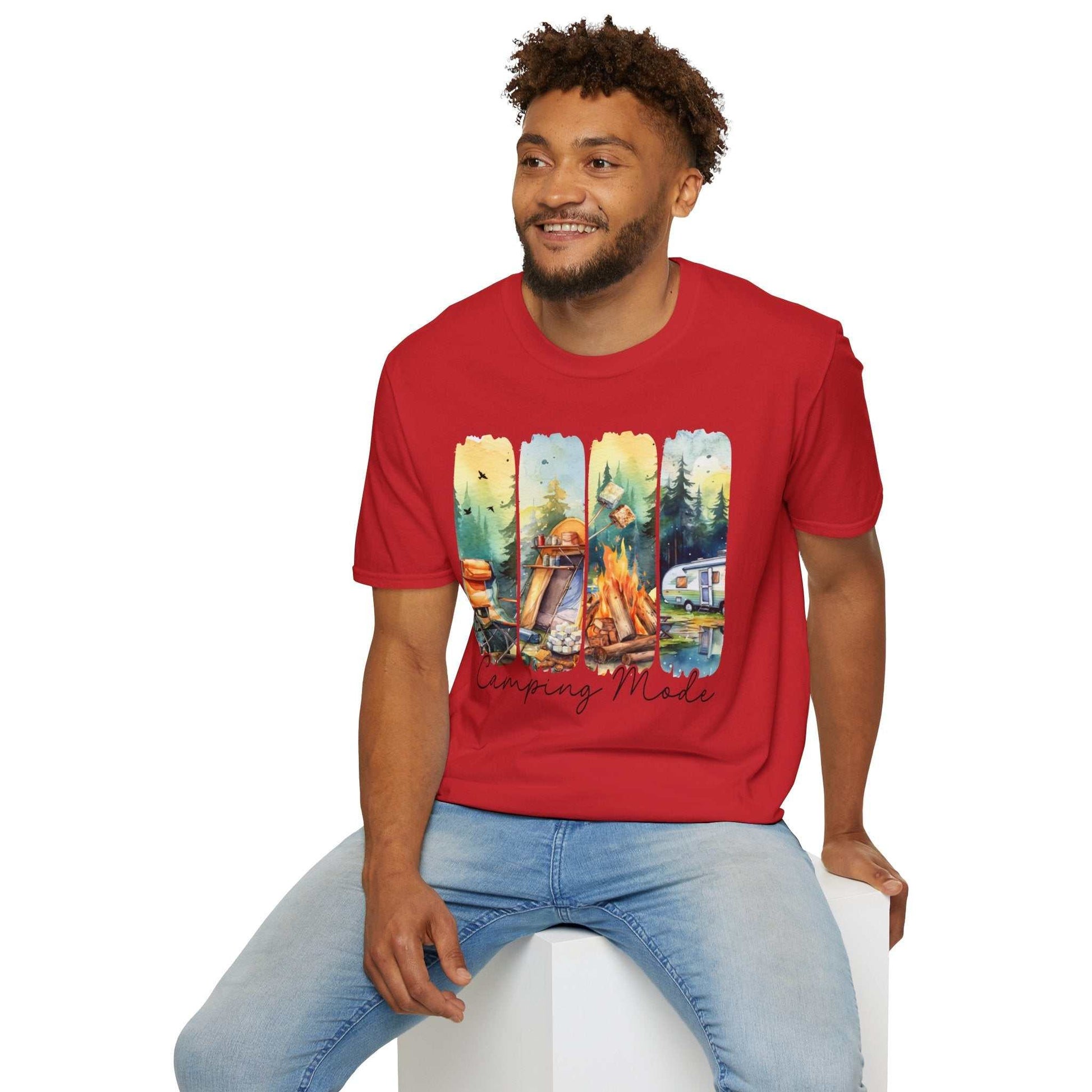 Man wearing red Camping Adventure Unisex T-Shirt with camping-themed print sitting on white cube