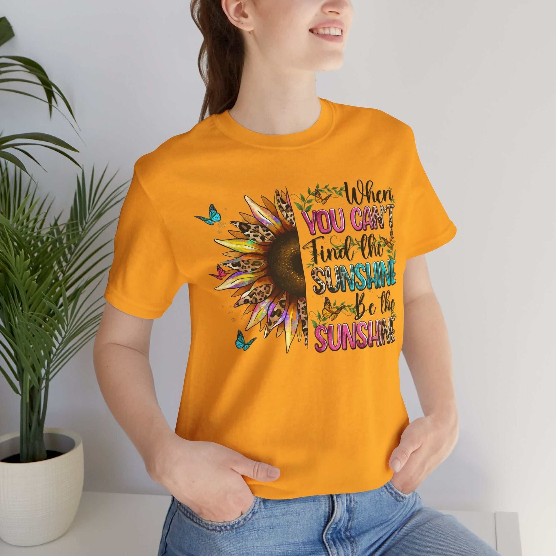Woman wearing bright orange Sunshine Quote Tee with colorful sunflower and positive text design