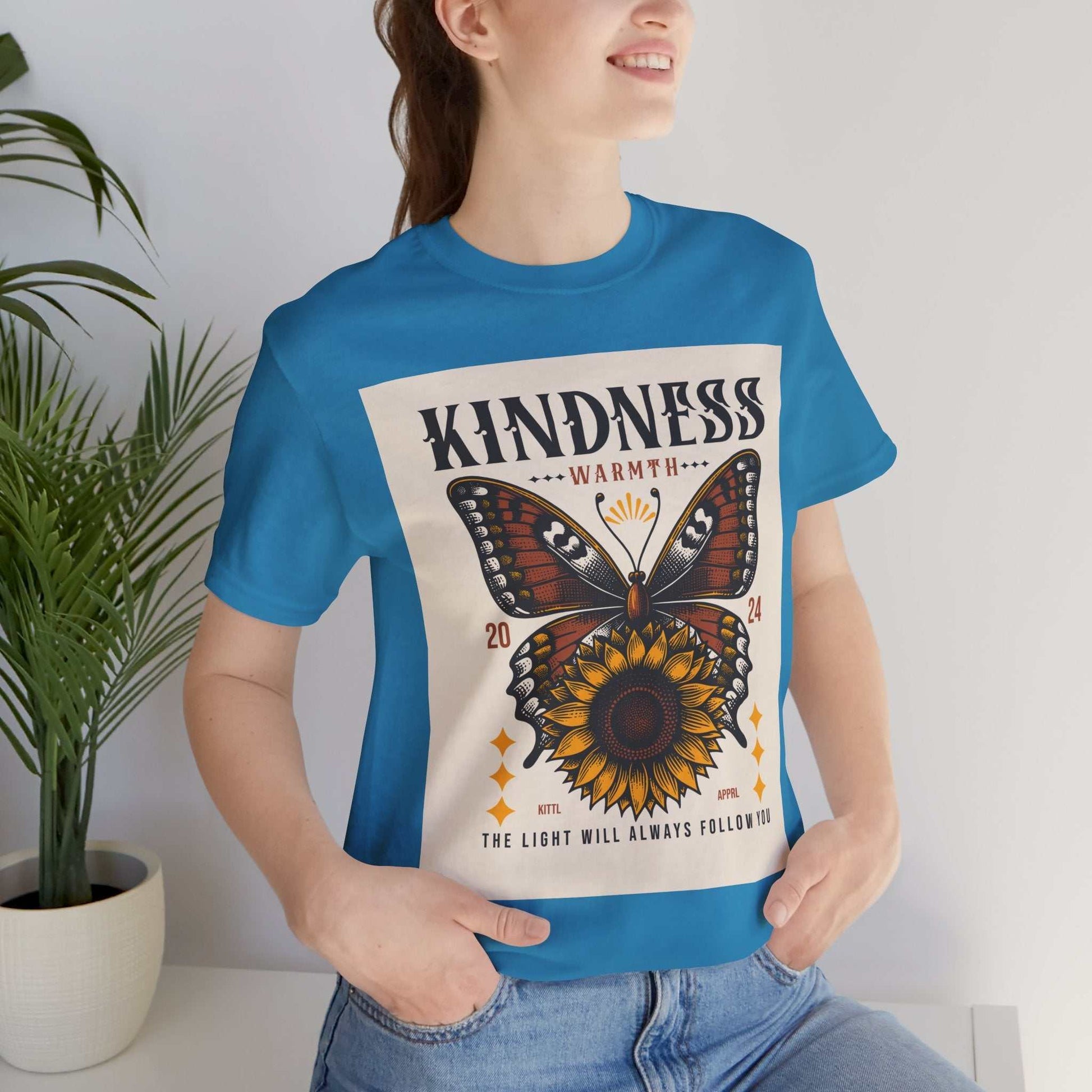Woman wearing blue Kindness Butterfly Tee featuring butterfly and sunflower design with inspirational text