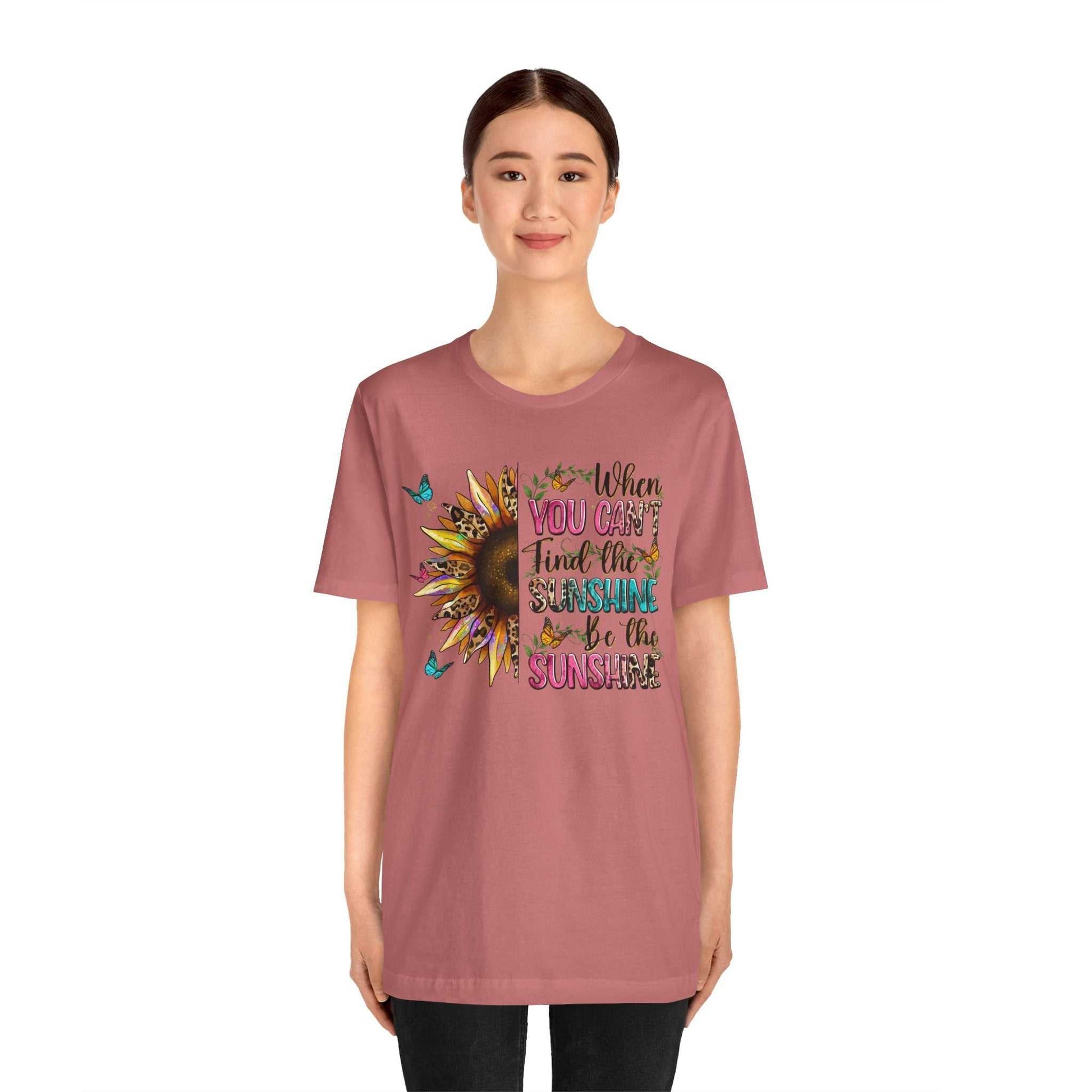 Woman wearing a dusty rose Sunshine Quote Tee with a vibrant sunflower and butterfly design and inspirational text on front