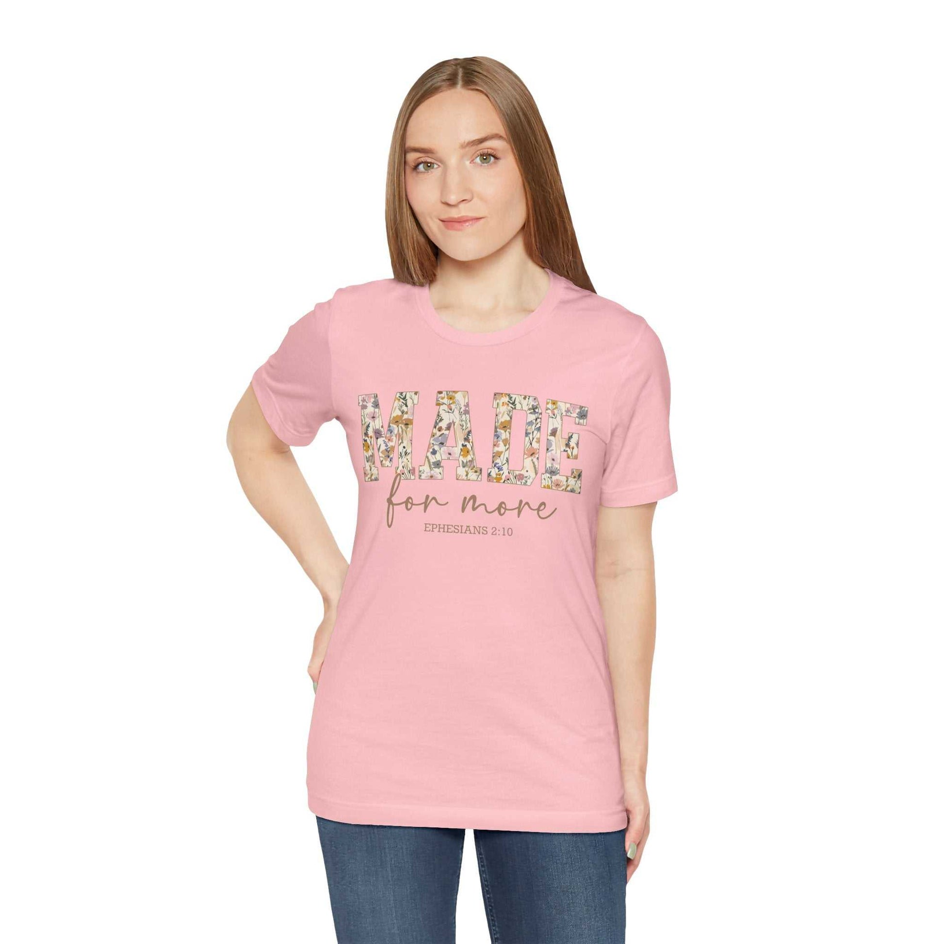 Woman wearing pink Made for More Tee with floral lettering and casual blue jeans