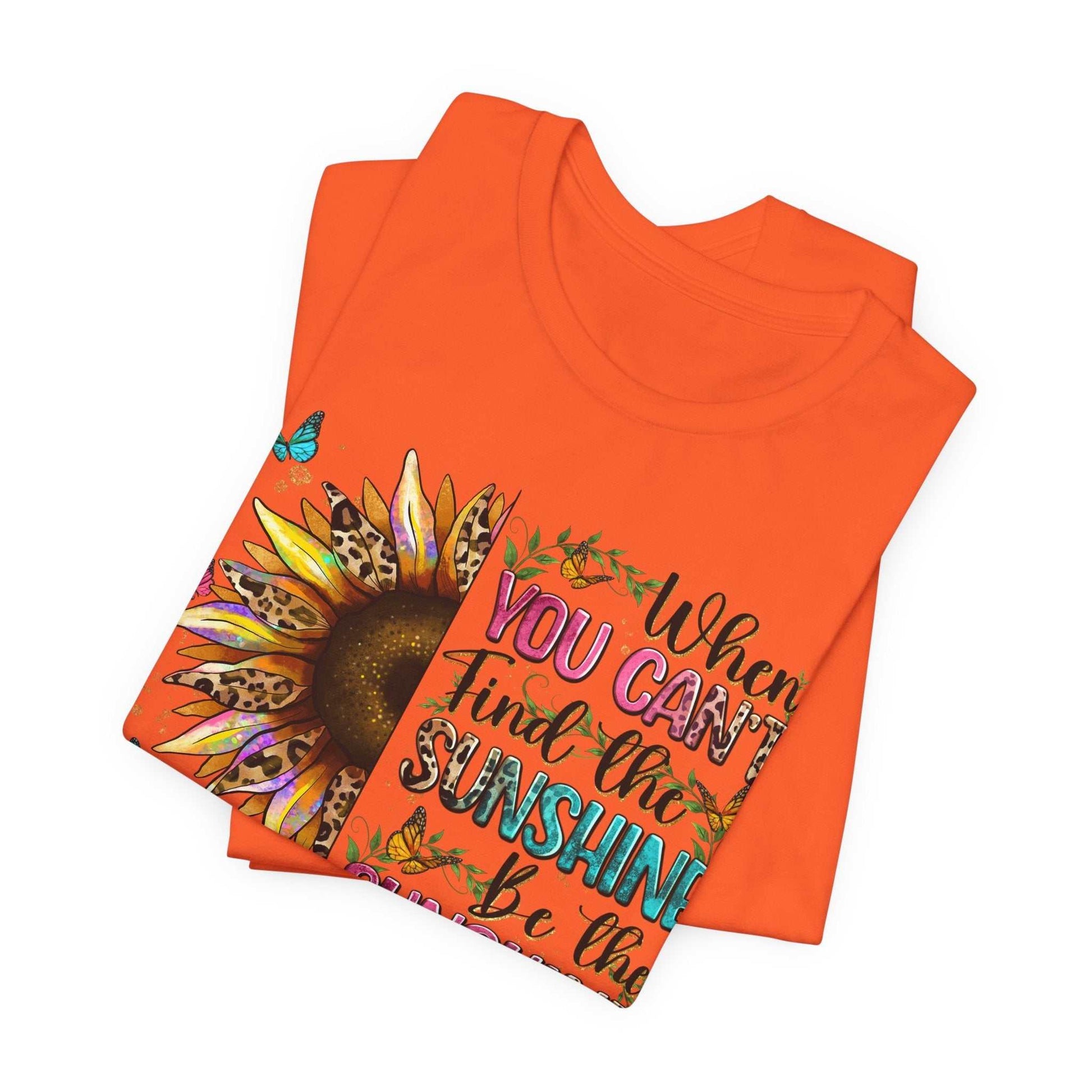 Orange Sunshine Quote Tee featuring a vibrant sunflower and motivational text design on a folded unisex short sleeve shirt