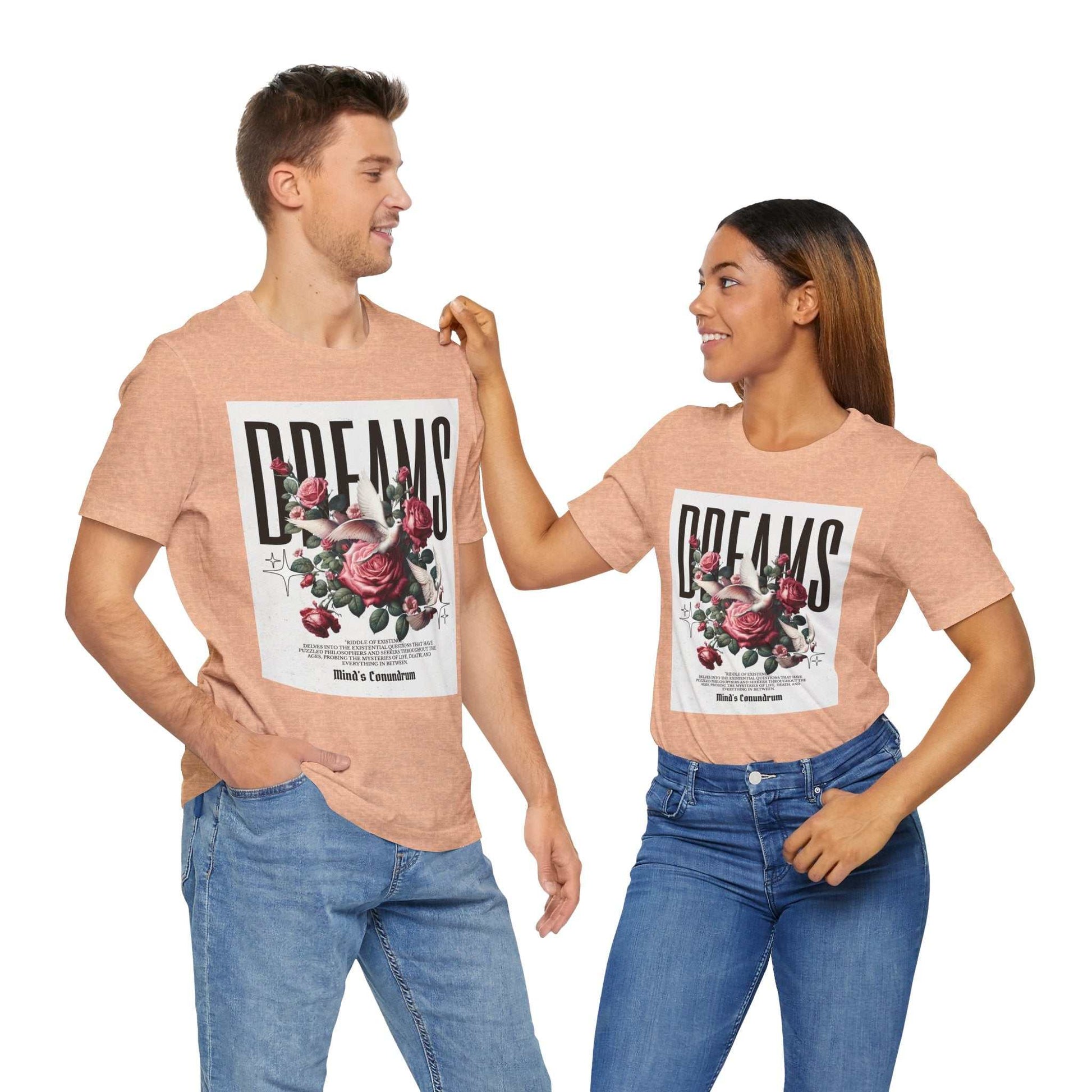 Two models wearing peach-colored Dreams Floral Tee with large floral and typography design on front, paired with blue jeans.