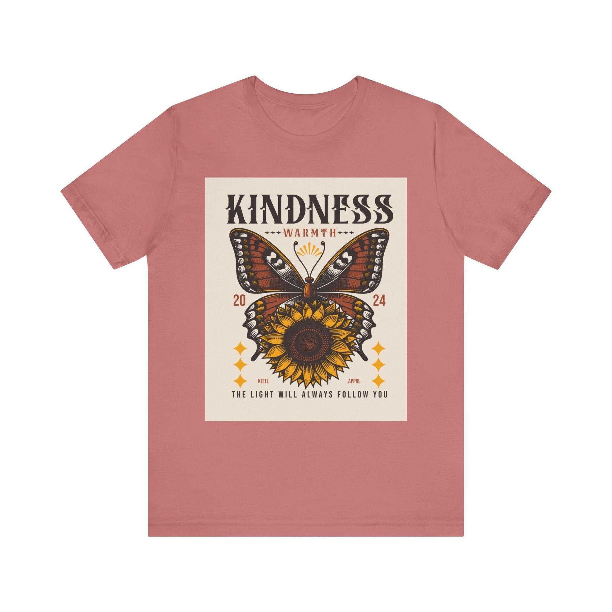 Unisex pink Kindness Butterfly Tee featuring a butterfly and sunflower graphic with the text "Kindness Warmth 2024 The light will always follow you"