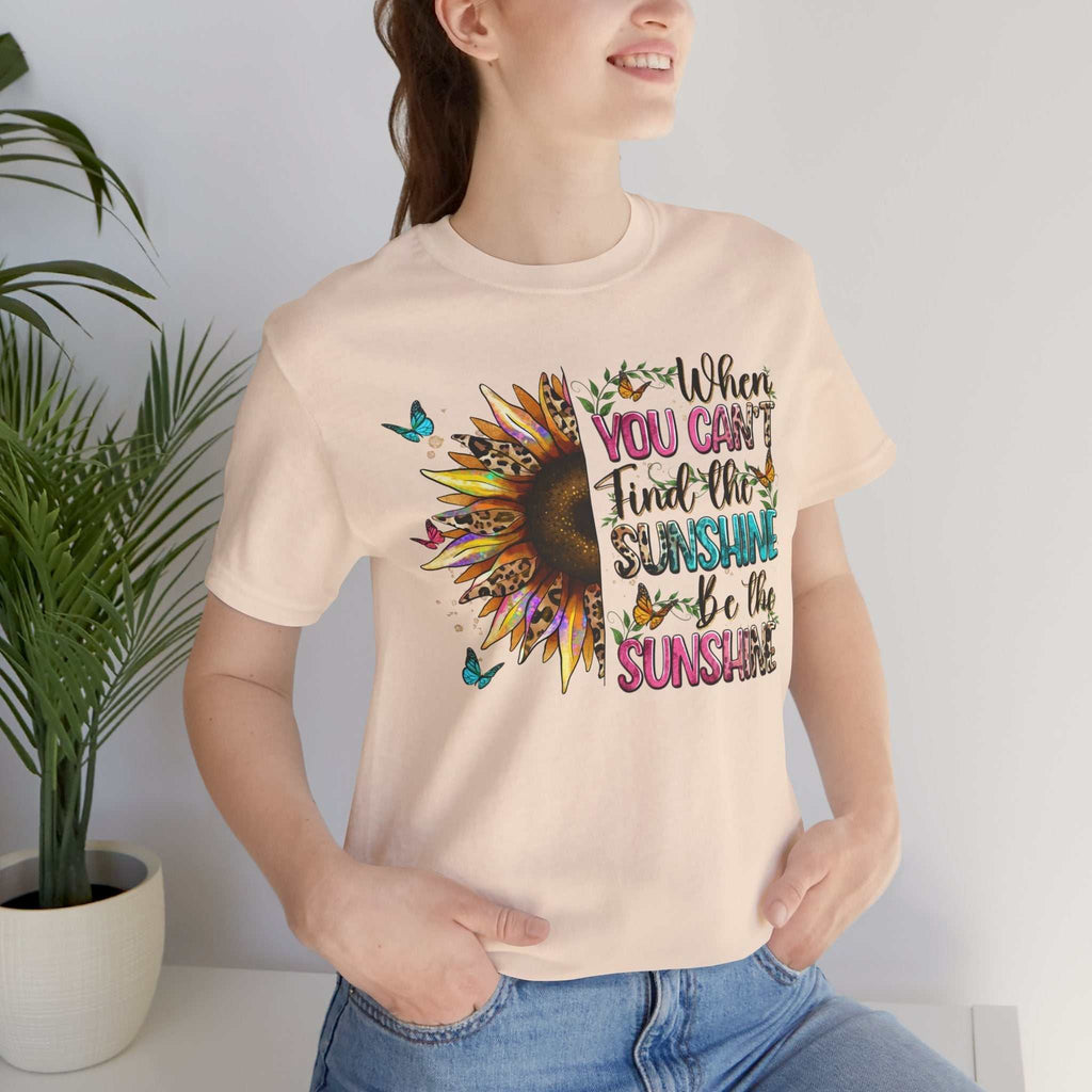 Woman wearing a light-colored Sunshine Quote Tee with a vibrant sunflower and motivational text design.