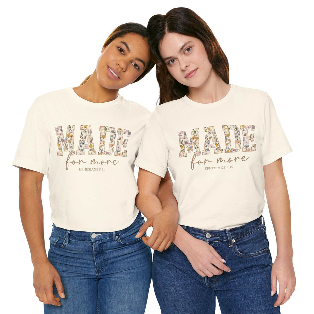 Two women wearing white Made for More Tee shirts with floral text design and scripture reference, styled with jeans.
