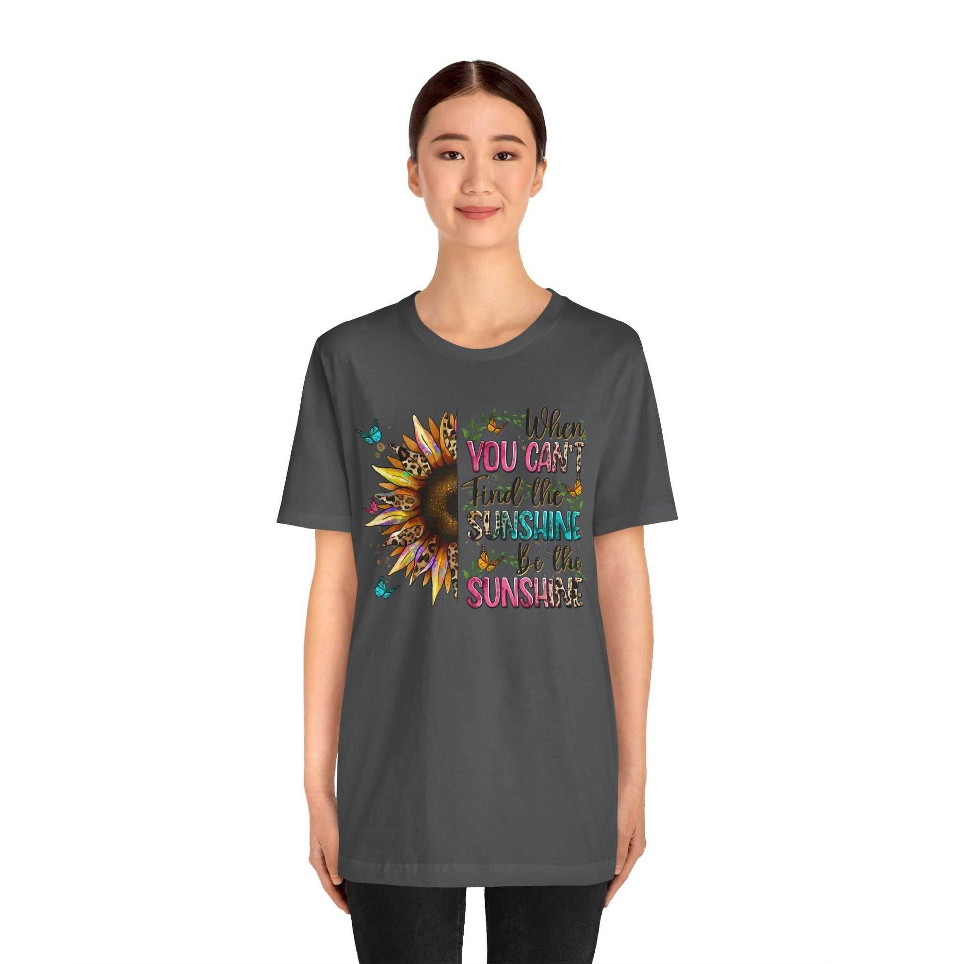 Woman wearing a dark grey Sunshine Quote Tee with colorful sunflower and inspirational text design on front