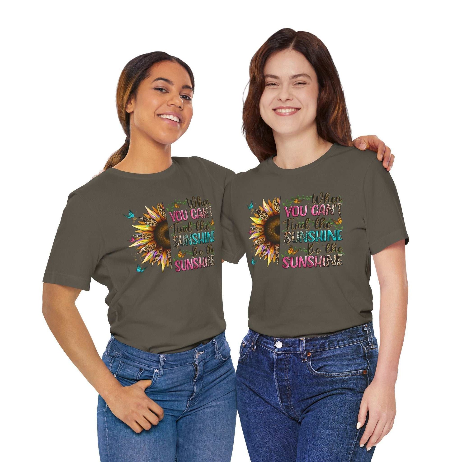 Two smiling women wearing olive green Sunshine Quote Tee with colorful sunflower and inspirational quote design