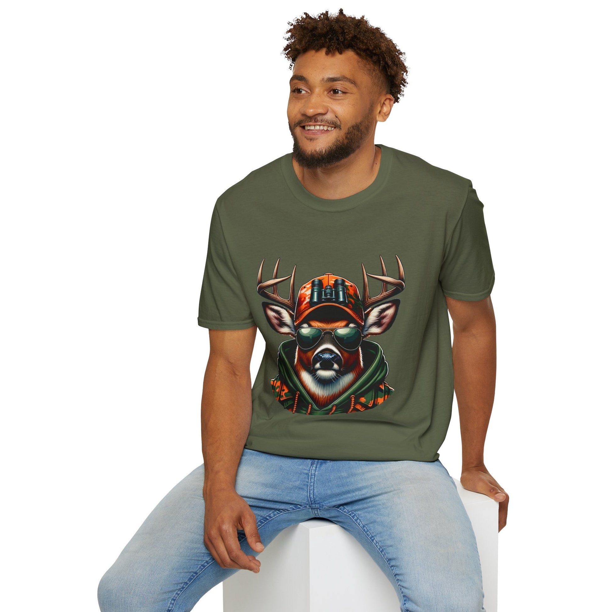 Man wearing olive green Hunting Enthast T-Shirt with graphic of a deer wearing sunglasses and camouflage hat sitting on white block