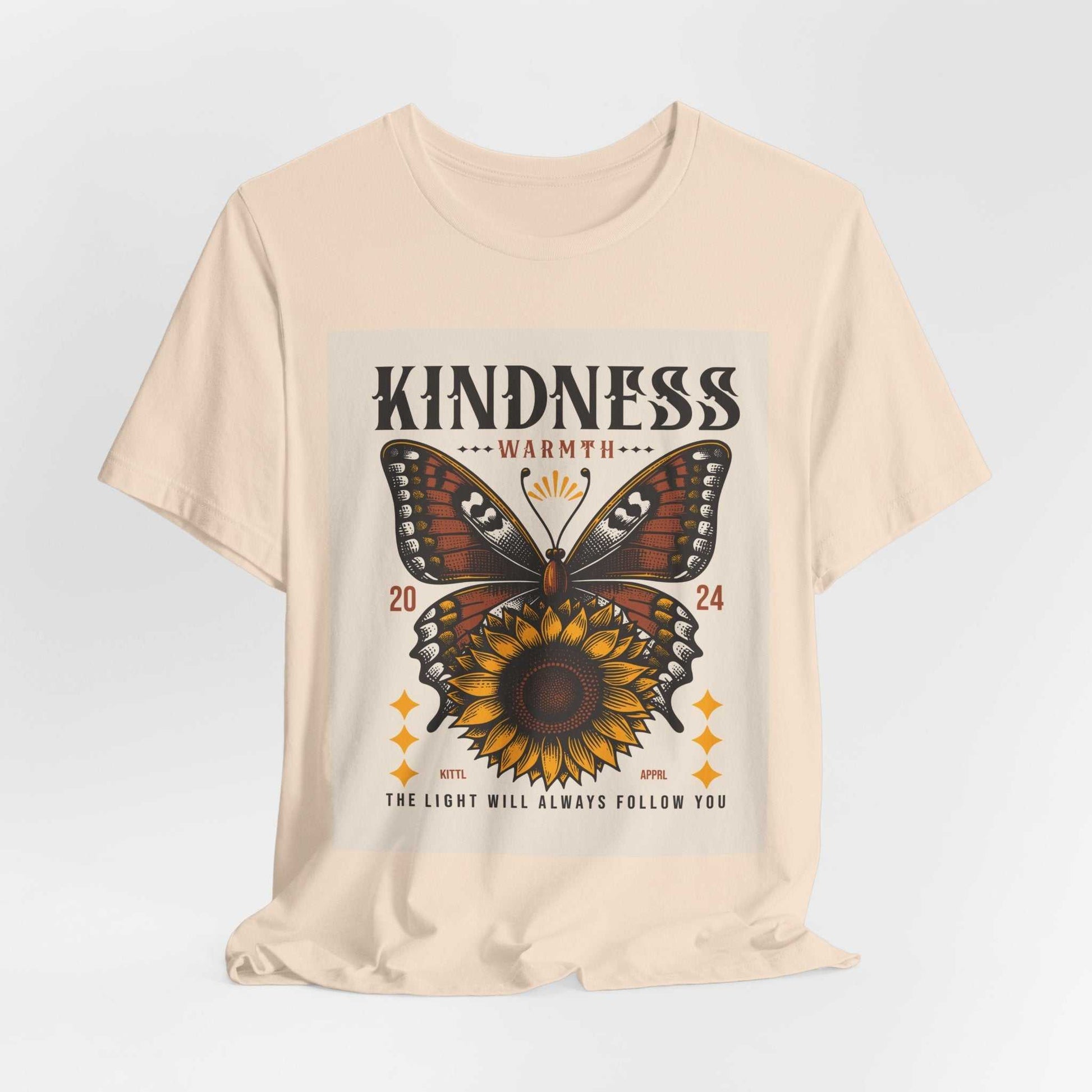 Beige Kindness Butterfly Tee featuring a large butterfly and sunflower graphic with the text "Kindness Warmth 2024" and "The light will always follow you" on the front