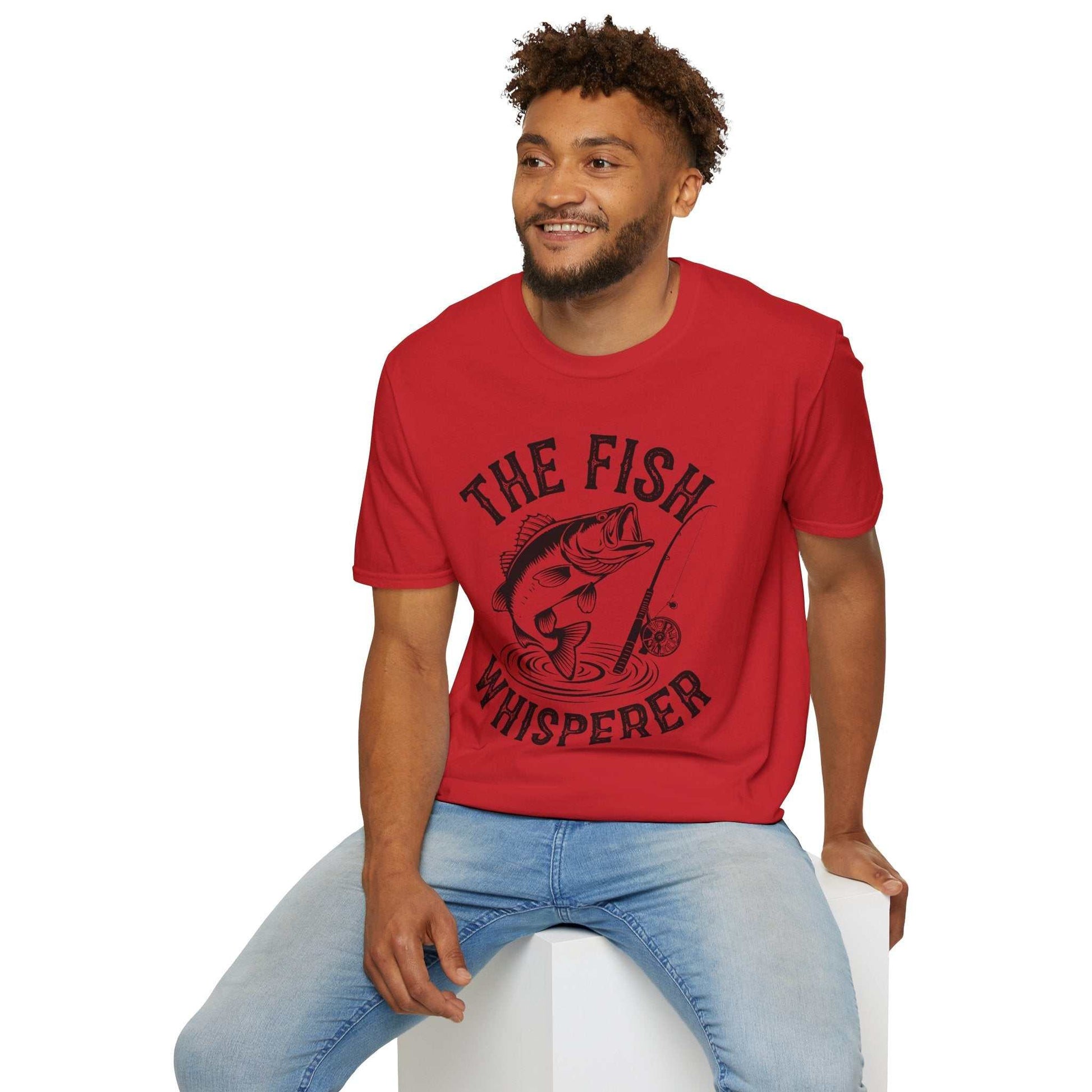 Unisex red softstyle t-shirt with "The Fish Whisperer" text and fishing graphic, made of 100% ring-spun cotton, comfortable and stylish for fishing enthusiasts.