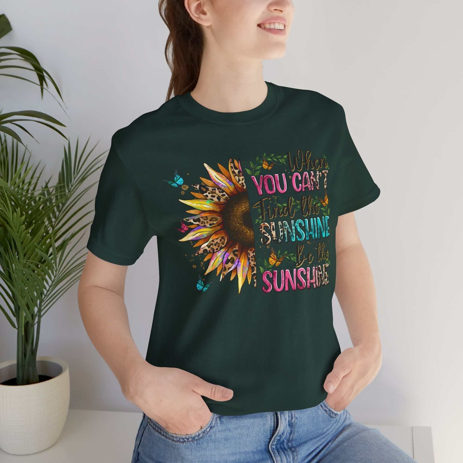 Woman wearing dark green Sunshine Quote Tee with vibrant sunflower and motivational text design, casual style