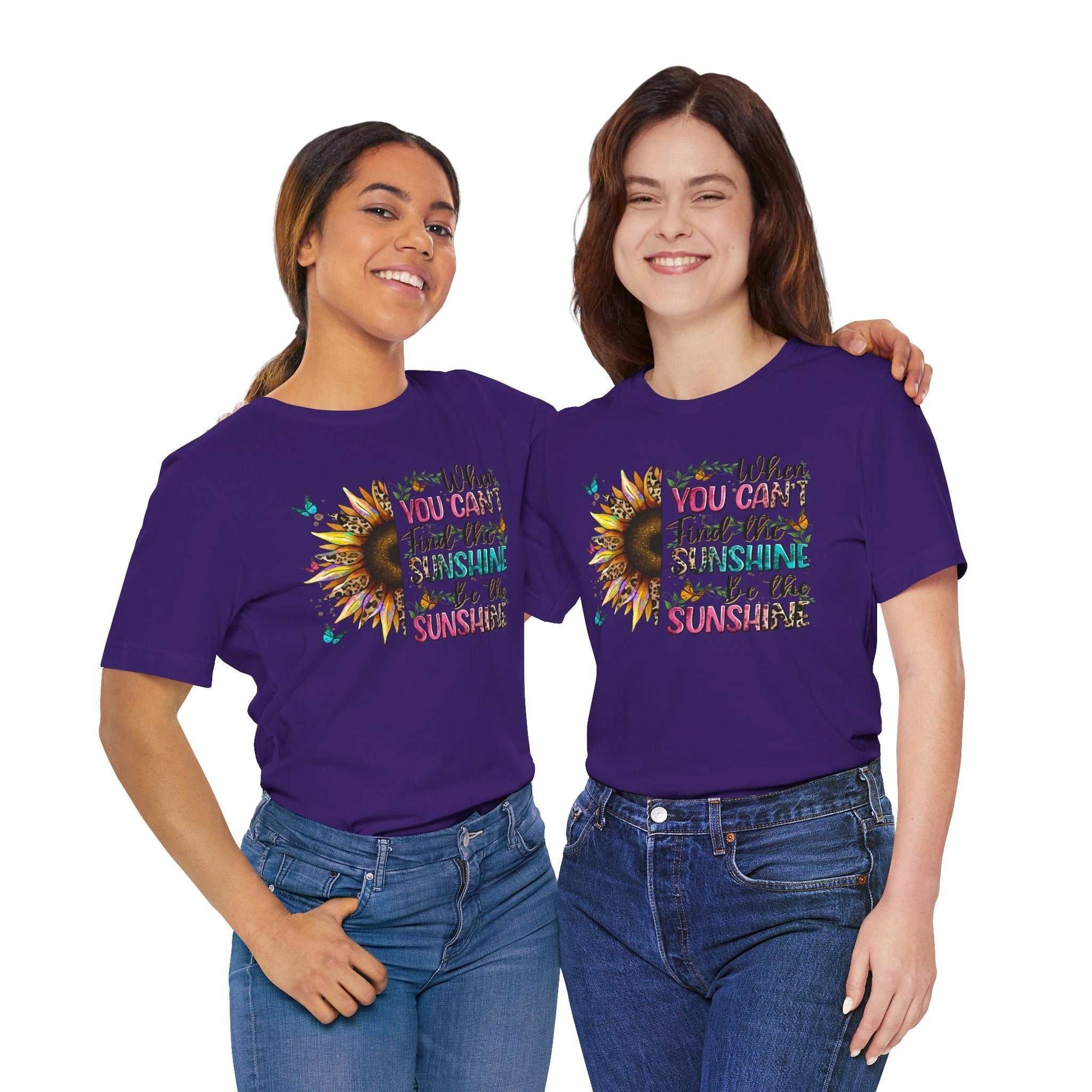 Two women wearing purple Sunshine Quote Tee shirts featuring a colorful sunflower design and the text "You can't stop the sunshine"