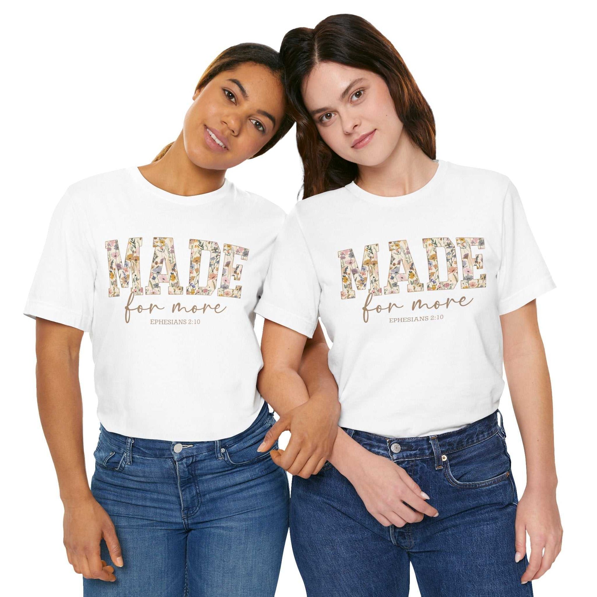 Two women wearing white Made for More Tee shirts with floral patterned "MADE" text and "for more EPHESIANS 2:10" printed below, paired with blue jeans, posing together against a white background