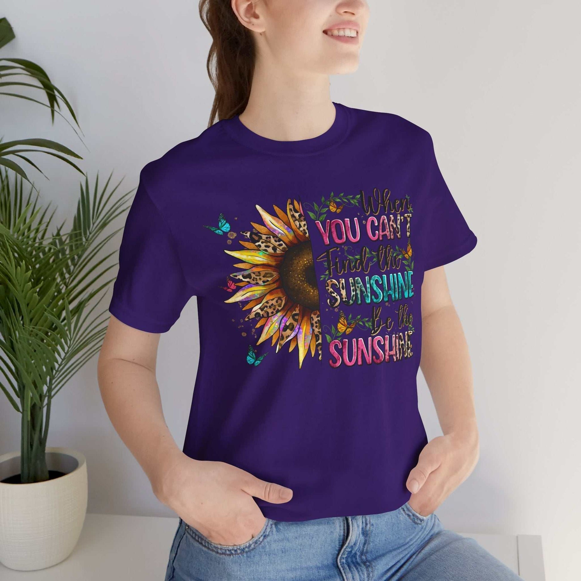 Woman wearing purple Sunshine Quote Tee with colorful sunflower and inspirational text design