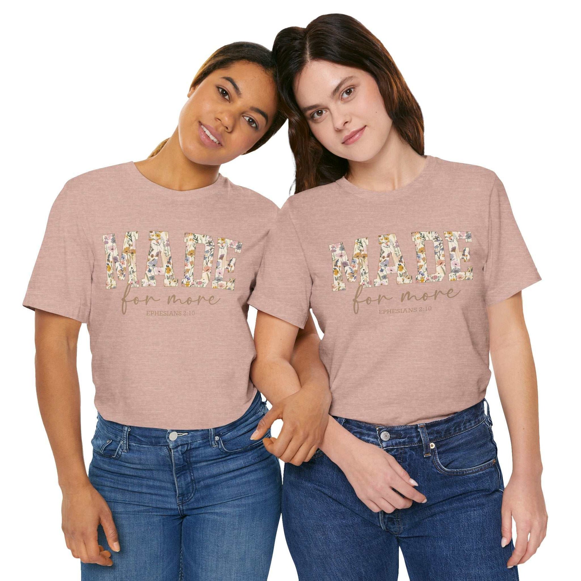 Two women wearing pink "Made for More" floral print unisex t-shirts paired with blue jeans