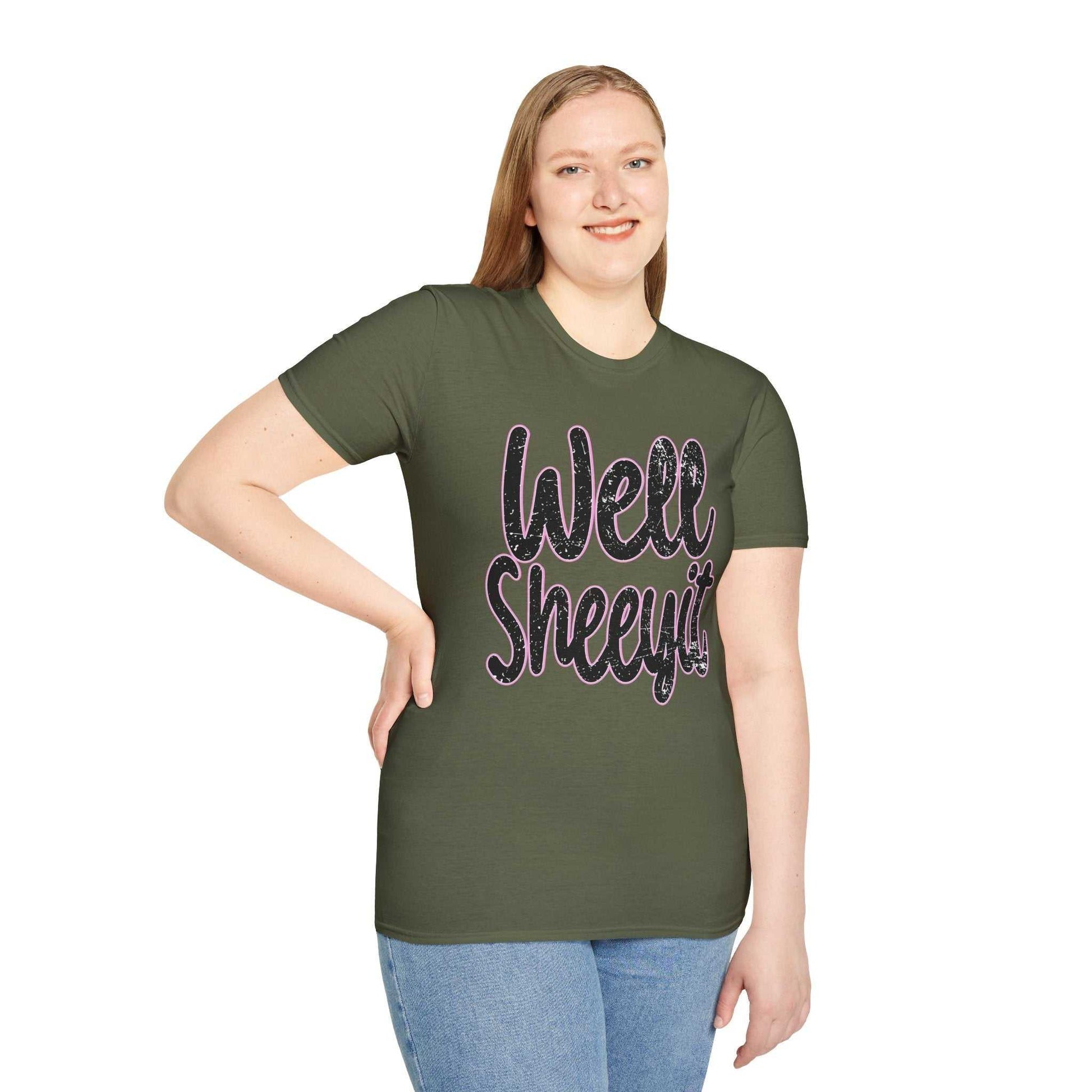Woman wearing an olive green casual statement tee with "Well Sheeyit" funny quote printed on the front, paired with blue jeans.