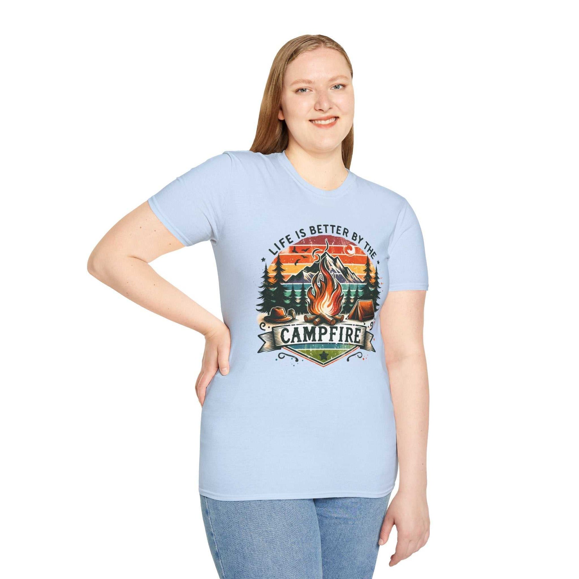Woman wearing light blue Camping Adventure Unisex T-Shirt with "Life is Better by the Campfire" and campfire graphic printed on front.