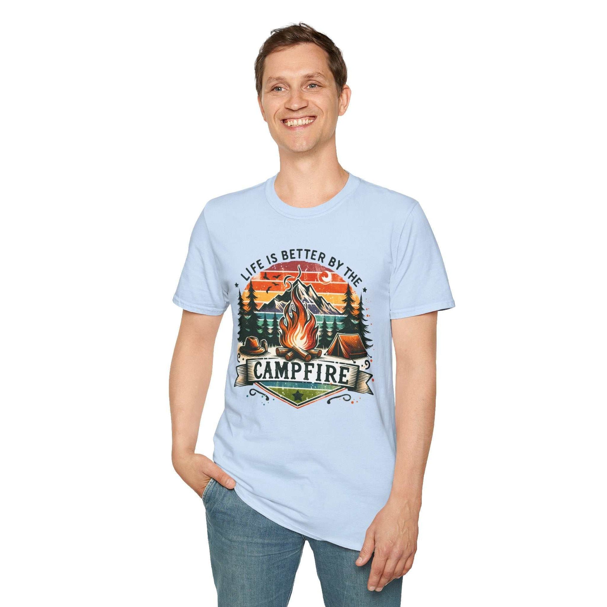 Unisex light blue camping adventure t-shirt with vibrant campfire design and "Life is better by the campfire" text, worn by smiling man