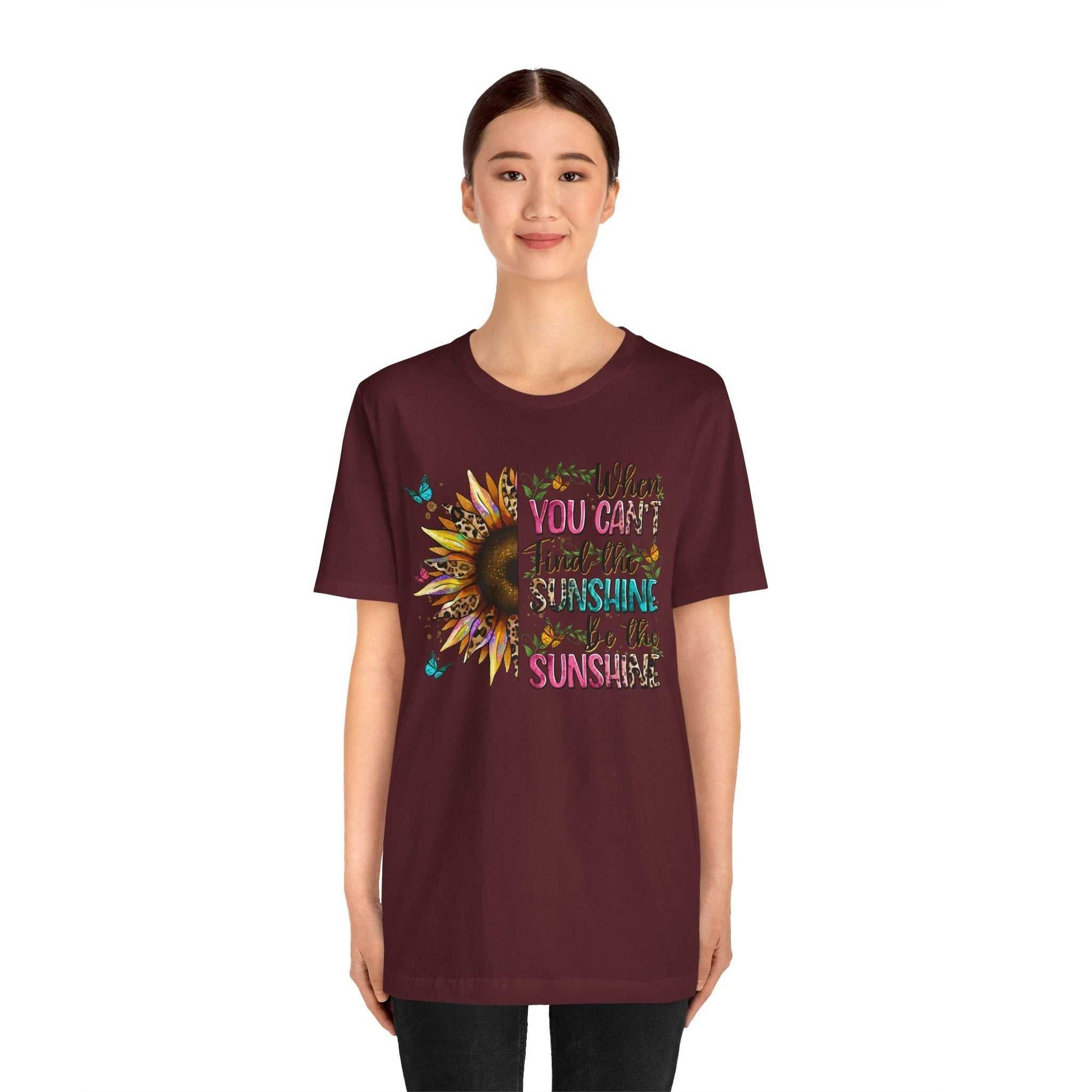 Woman wearing maroon Sunshine Quote Tee with colorful sunflower and uplifting text design