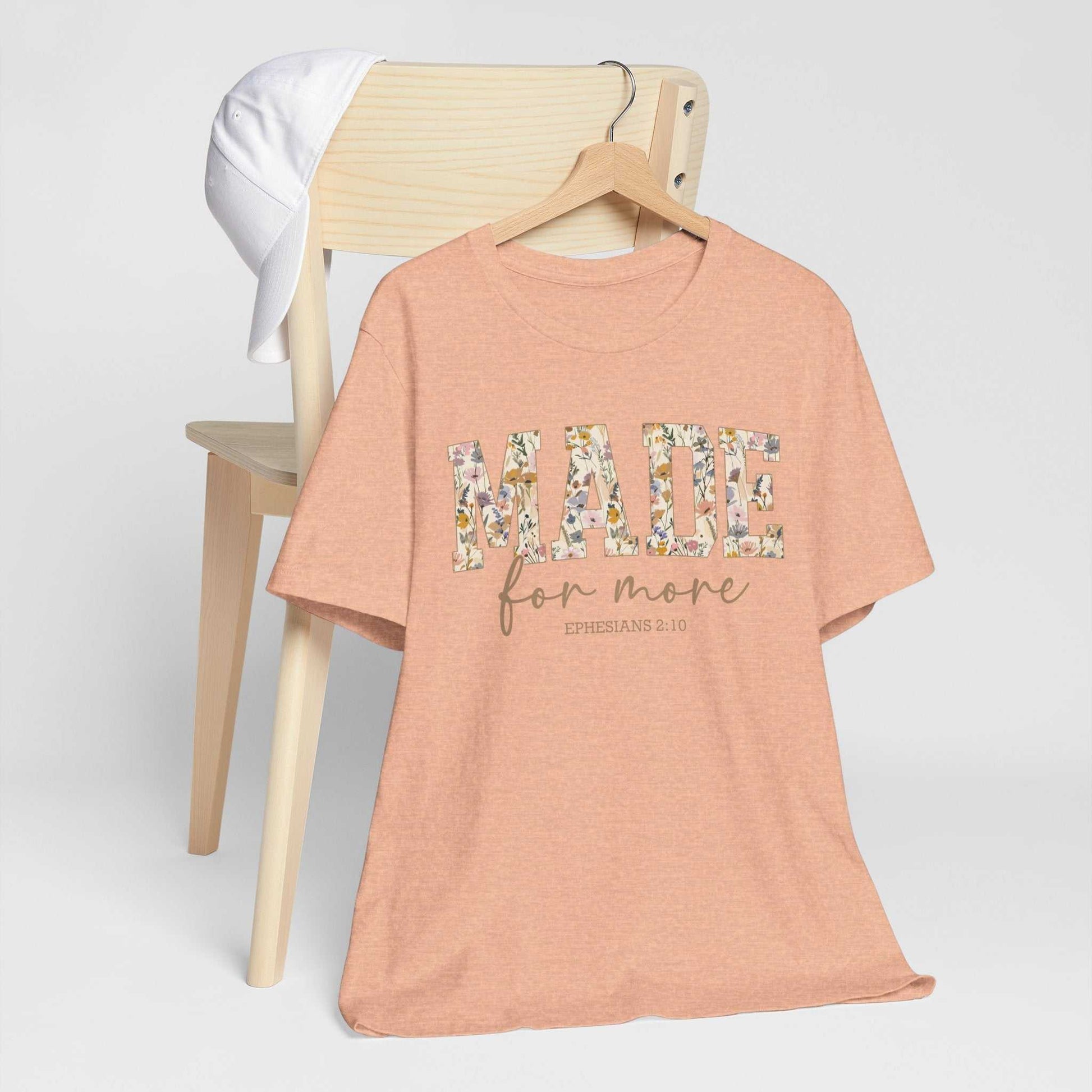 Made for More Tee peach floral print unisex short sleeve shirt on wooden chair with white cap background