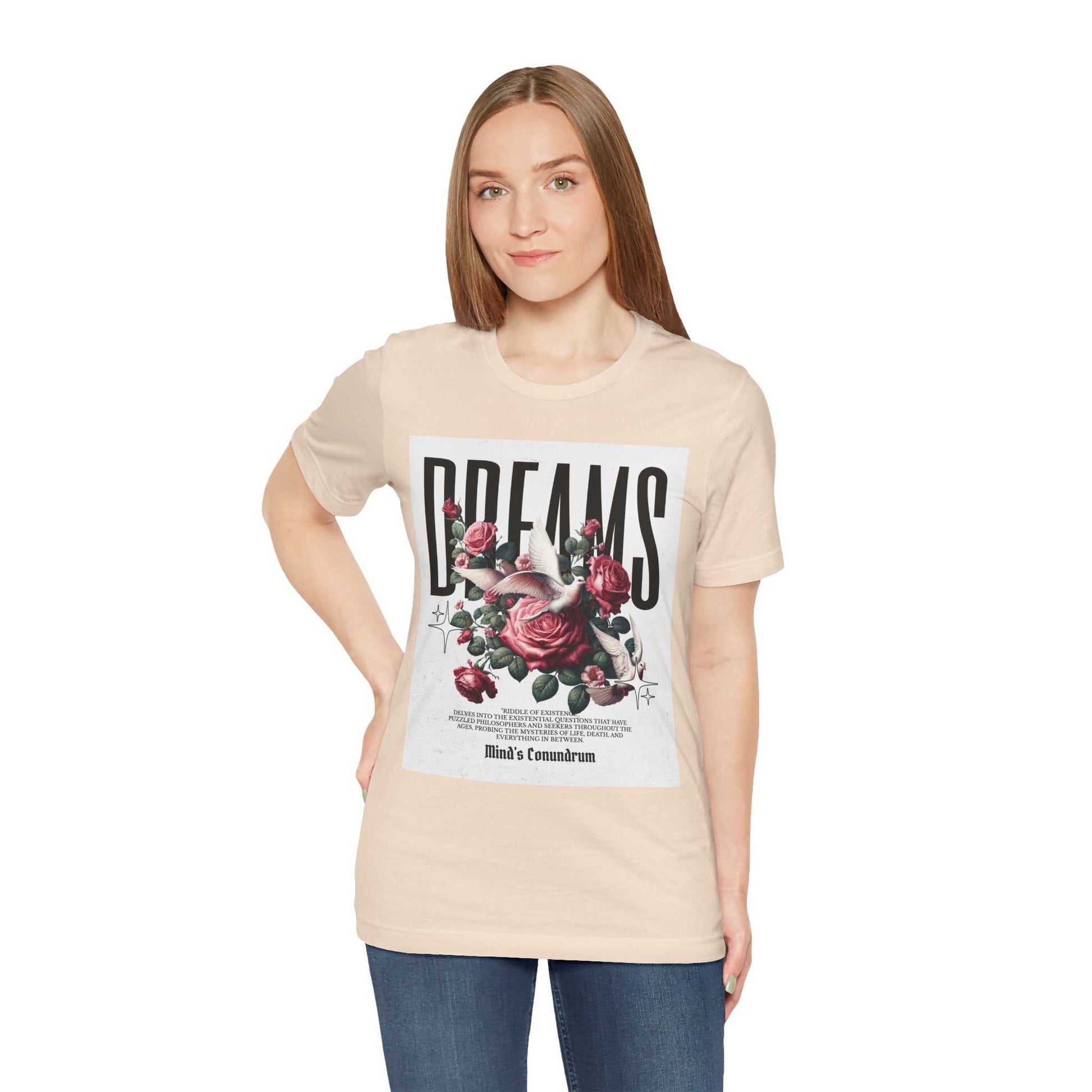Woman wearing a beige Dreams Floral Tee with a large floral graphic and bold typography on the front, paired with blue jeans.