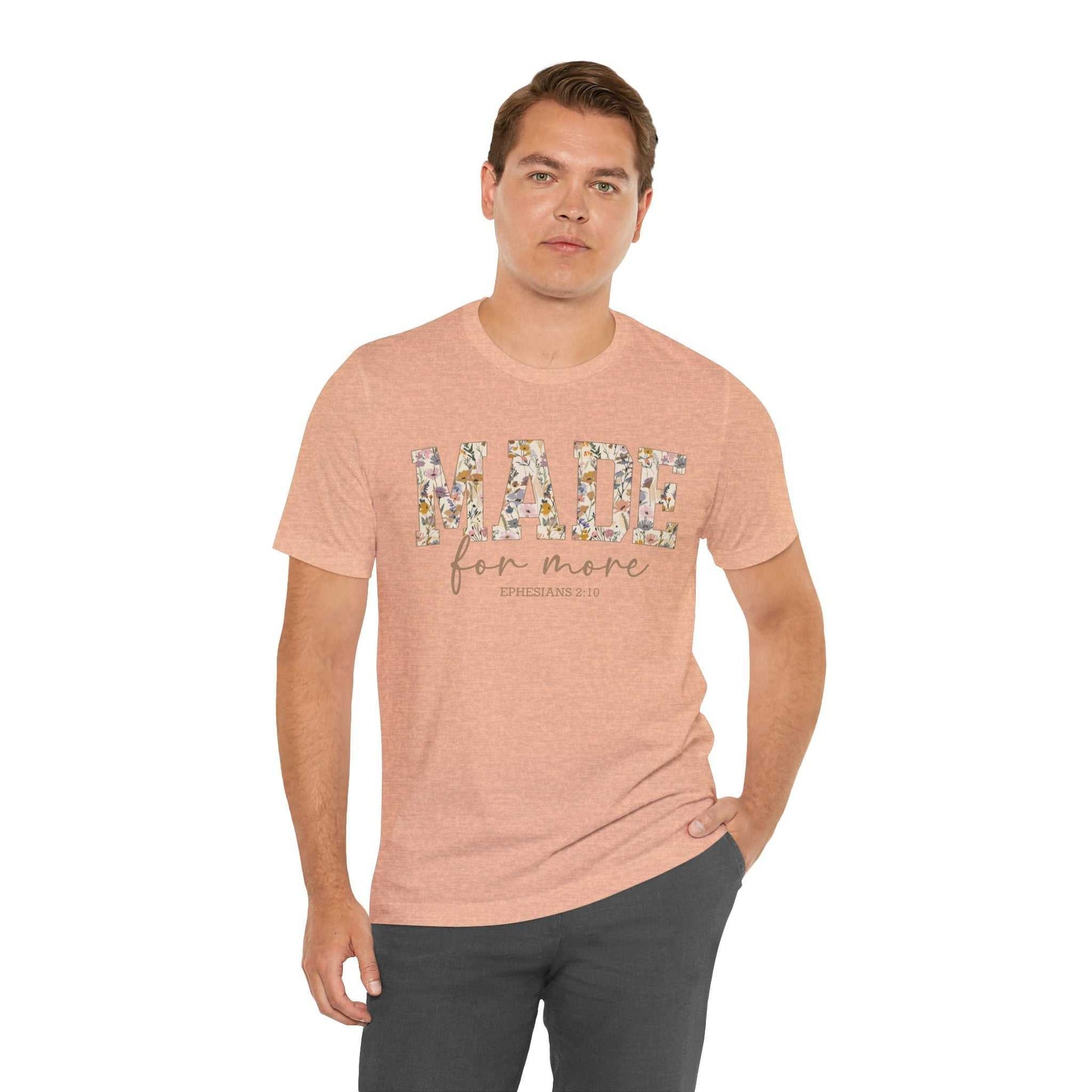Man wearing a peach Made for More Tee with floral text design and casual fit.