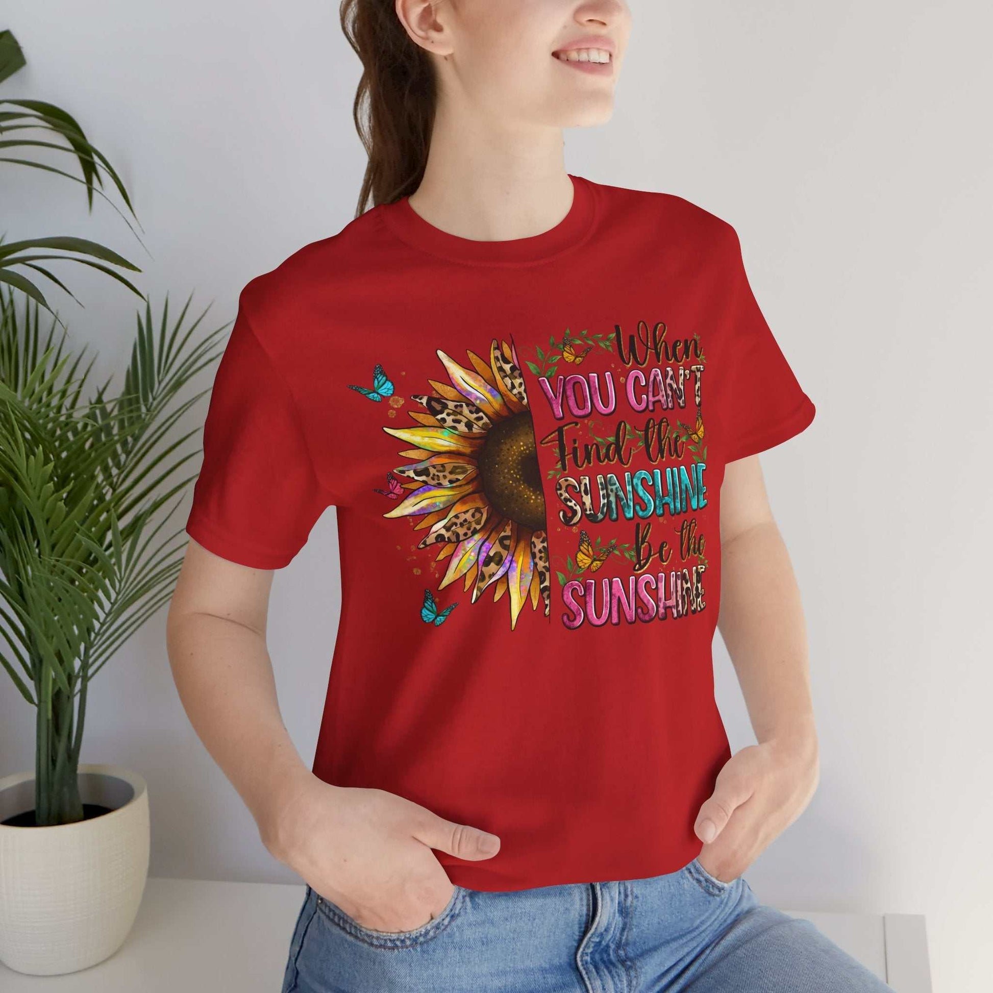 Red Sunshine Quote Tee with vibrant sunflower and motivational text design, worn by a smiling woman