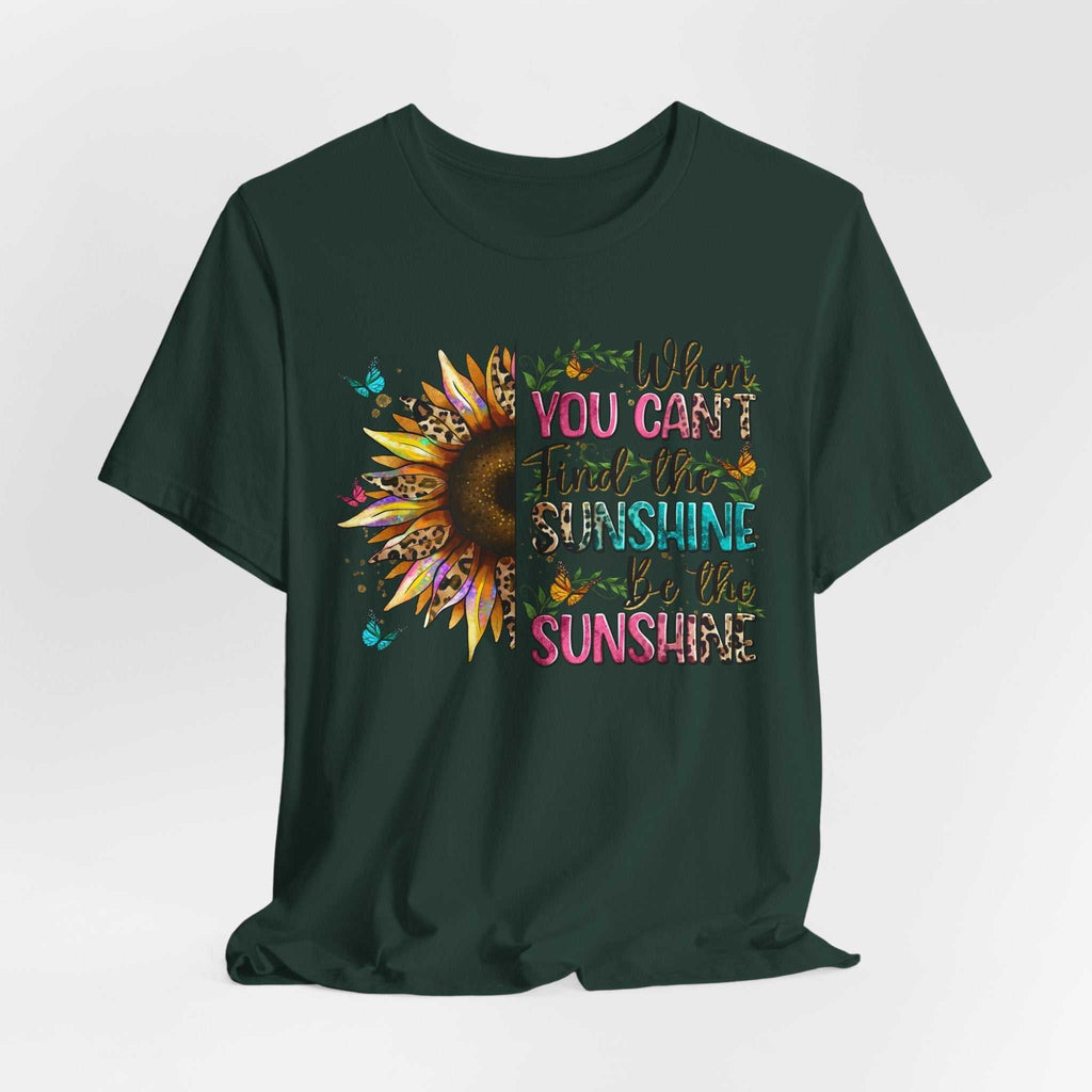 Dark green unisex tee featuring a colorful sunflower and the inspirational quote "When you can't find the sunshine be the sunshine" design