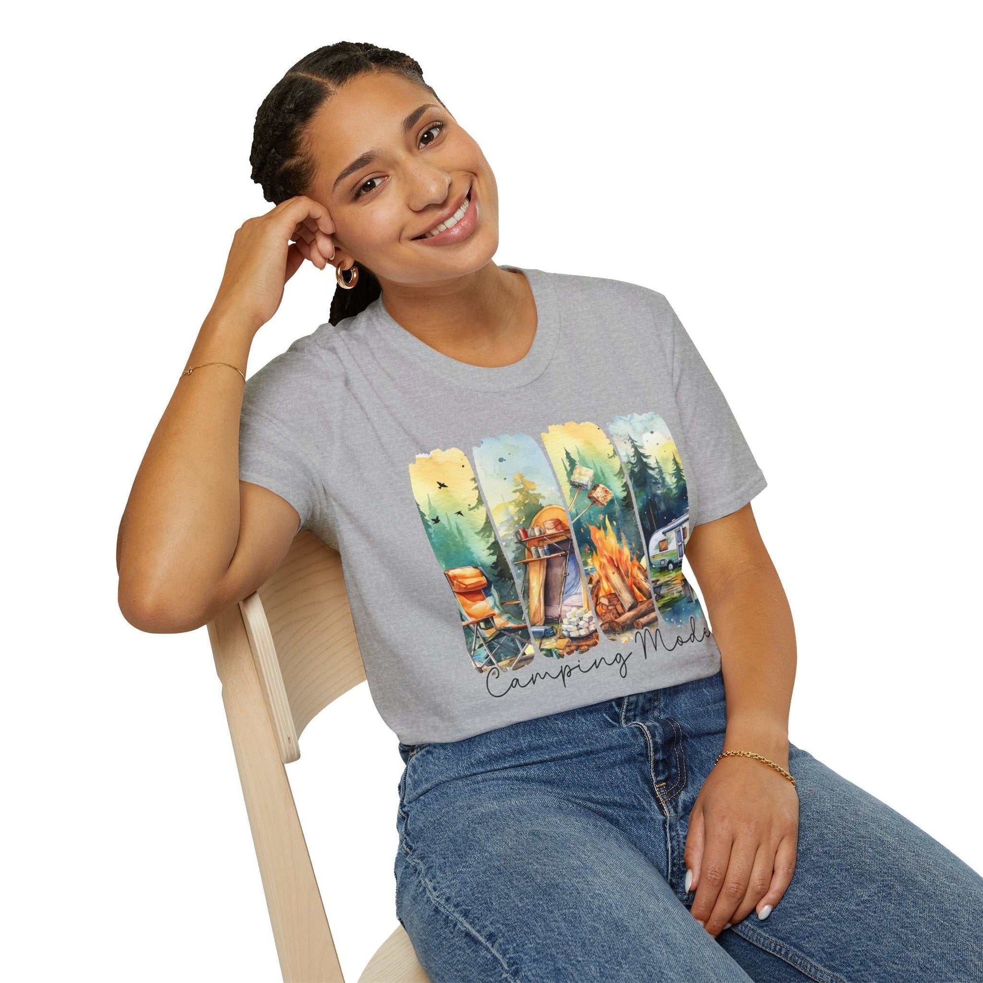 woman wearing gray Camping Adventure Unisex T-Shirt with colorful camping-themed graphic sitting on chair smiling