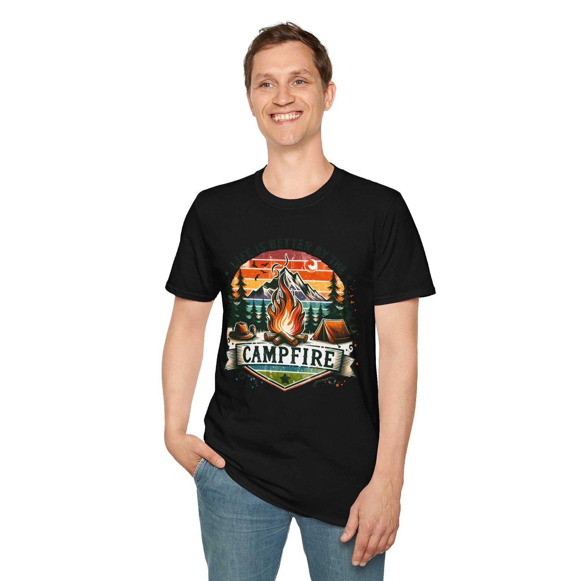Man wearing black Camping Adventure Unisex T-Shirt with "Life is Better by the Campfire" design featuring a campfire, trees, and sunset.