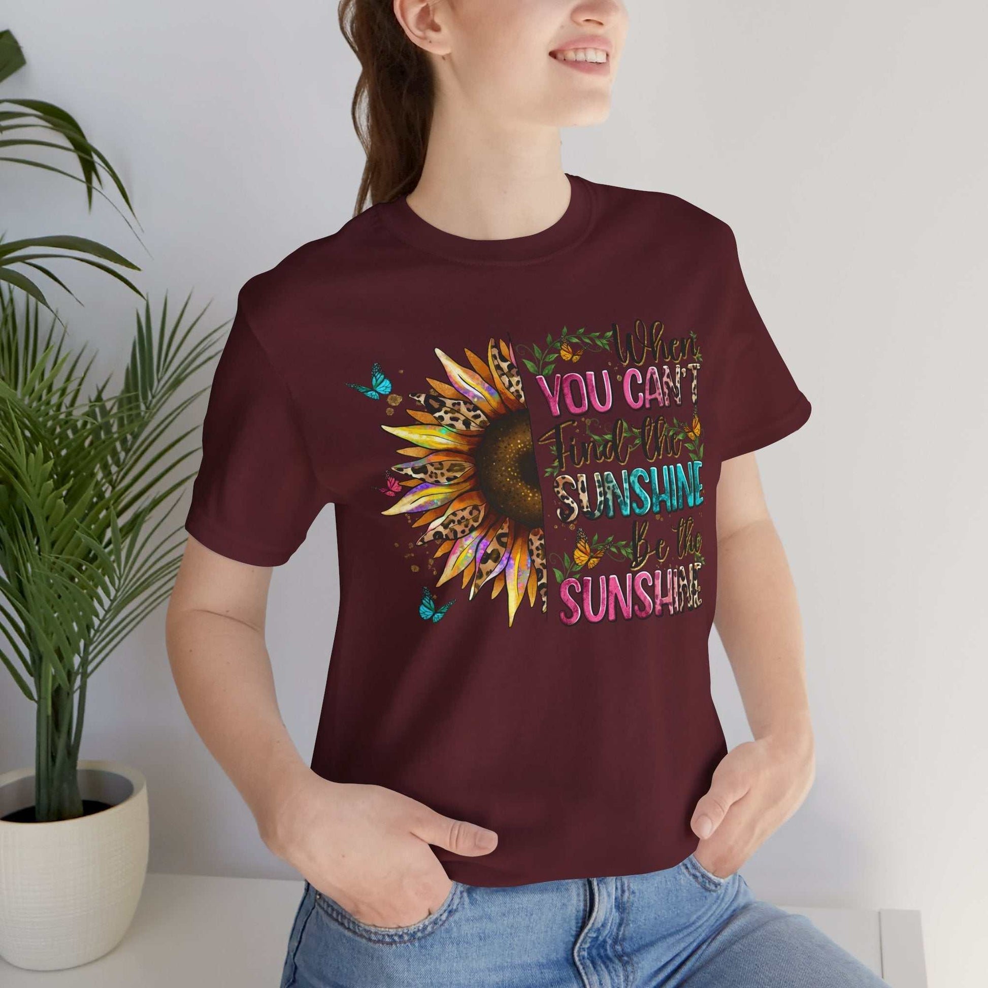 Woman wearing maroon Sunshine Quote Tee with colorful sunflower and inspirational text design